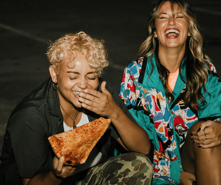 Friends laughing and sharing pizza