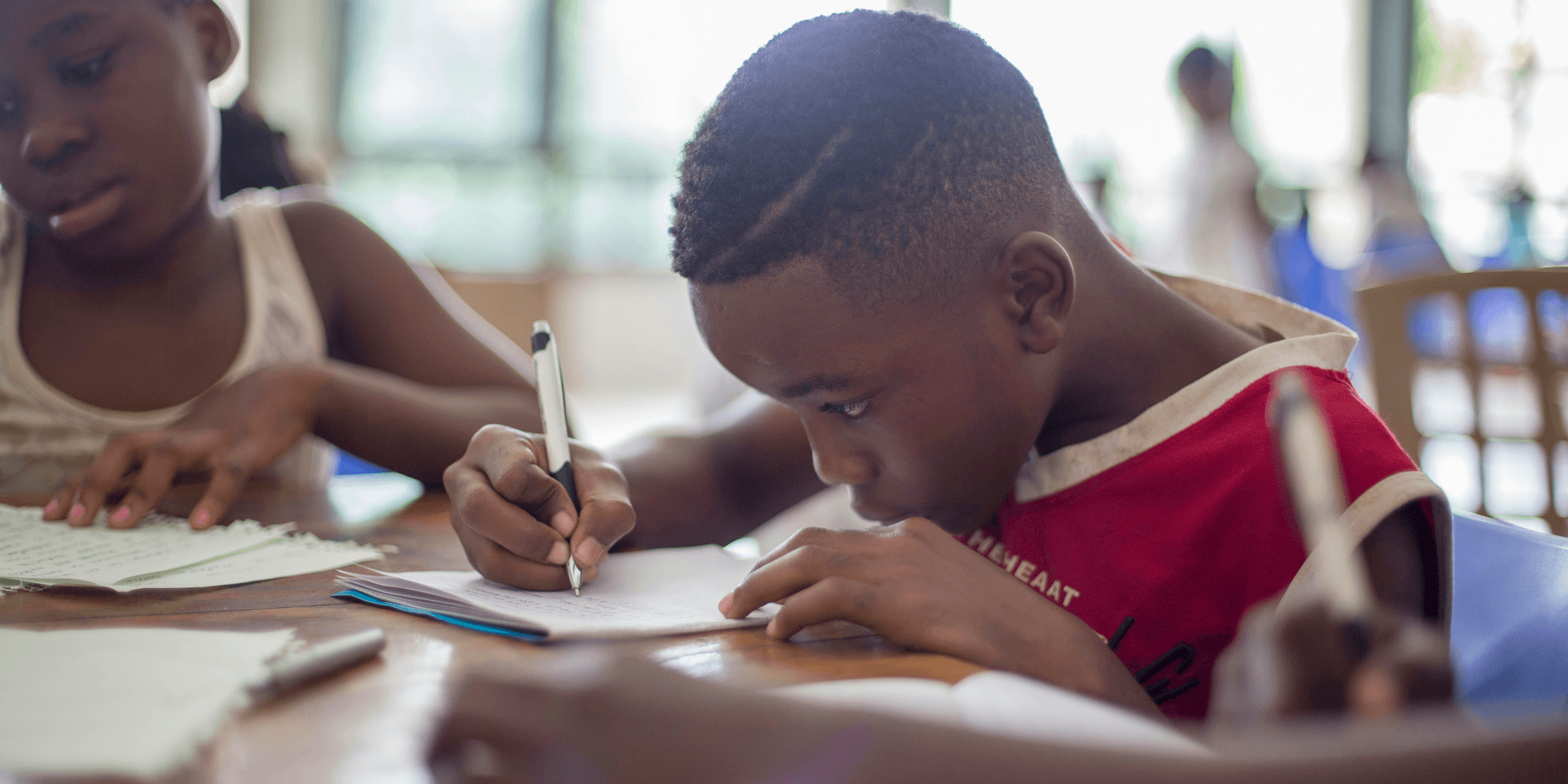 boy writing on printer paper near girl