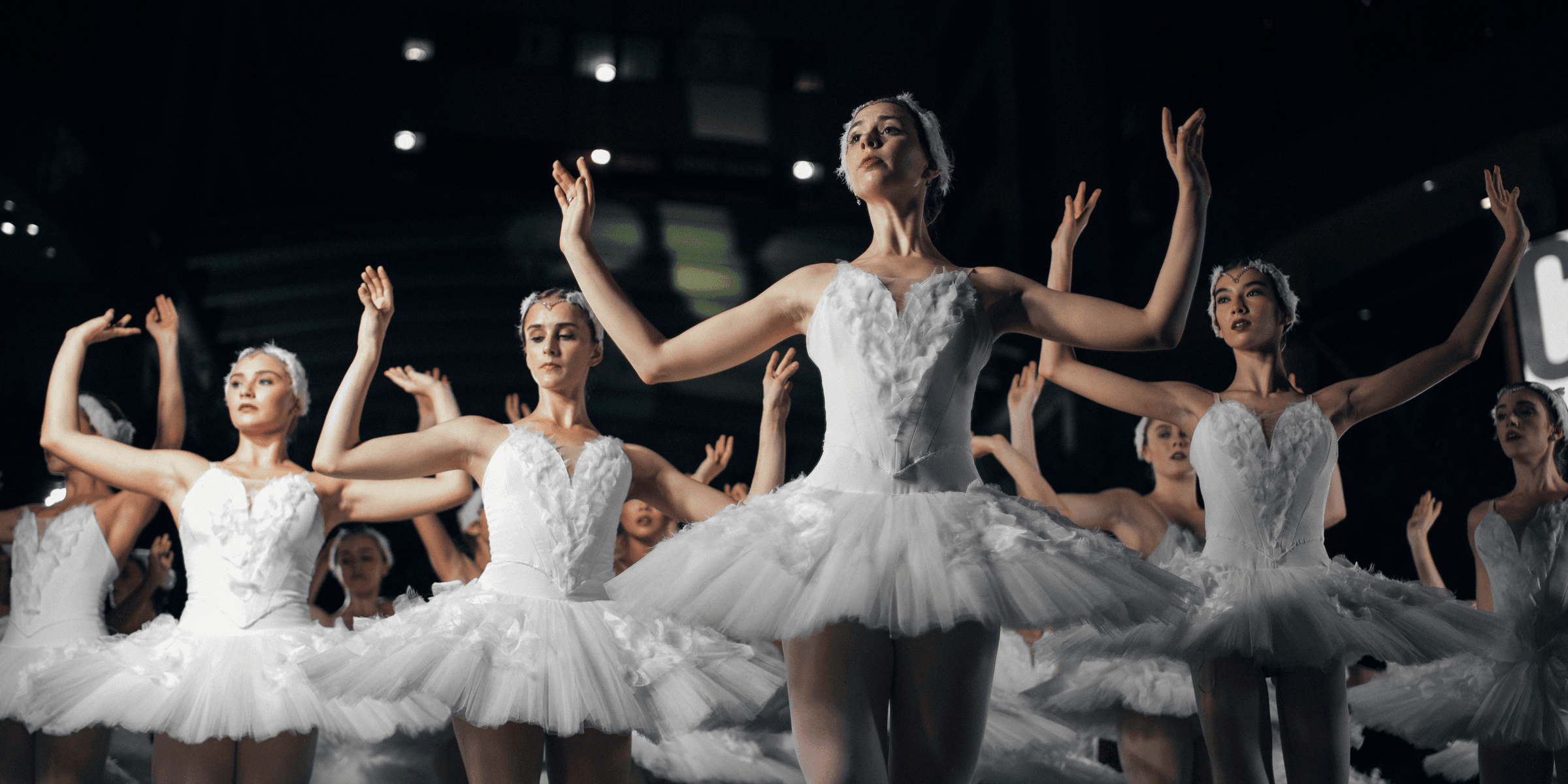 group of ballerinas dancing while raising both hands