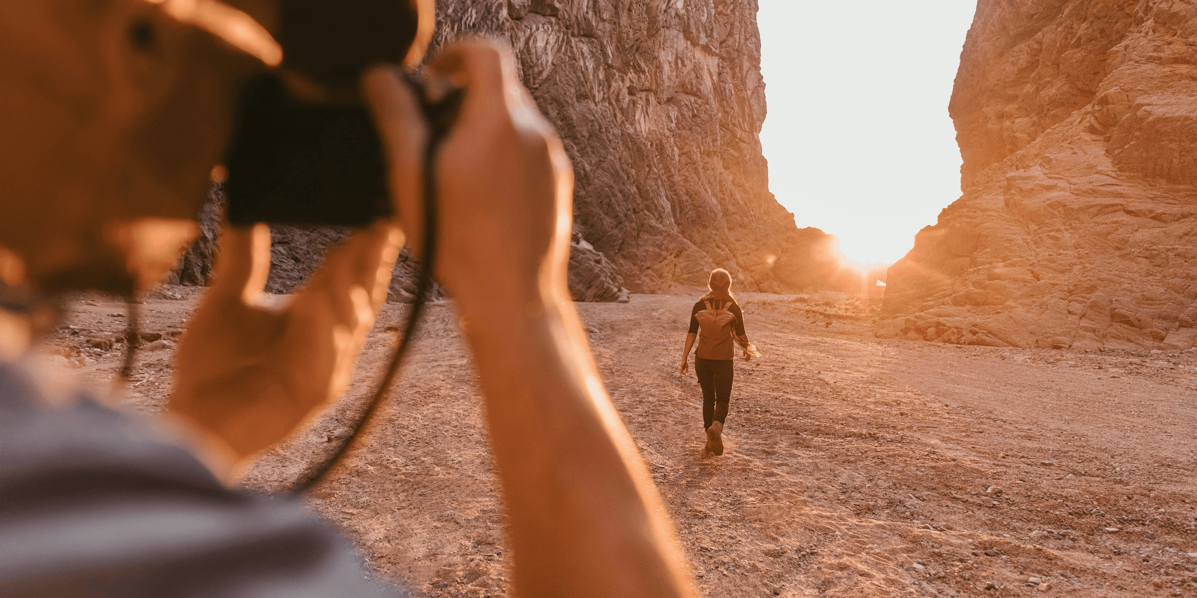 a man taking a picture of a woman in the desert