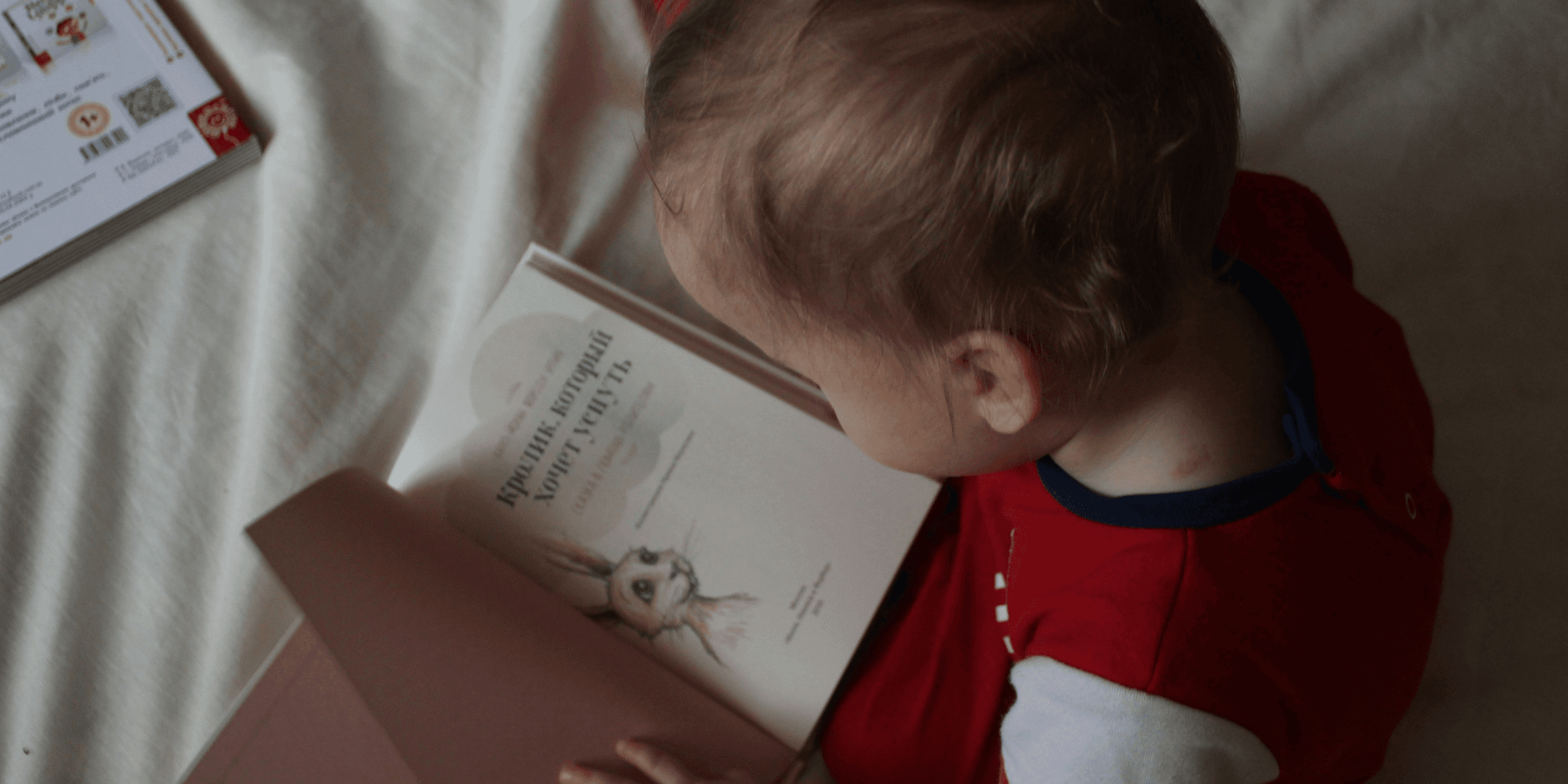 baby sitting on bed while reading on book