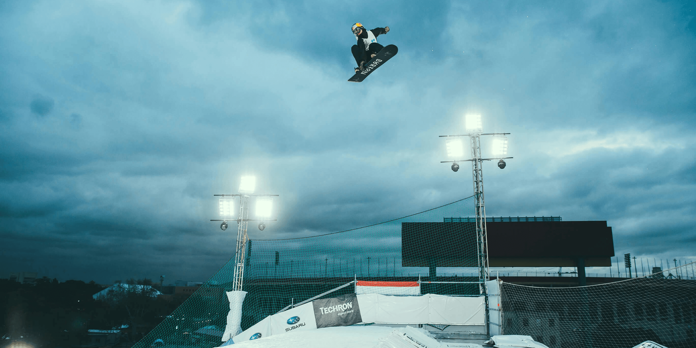 person snowboarding in mid air under cloudy sky