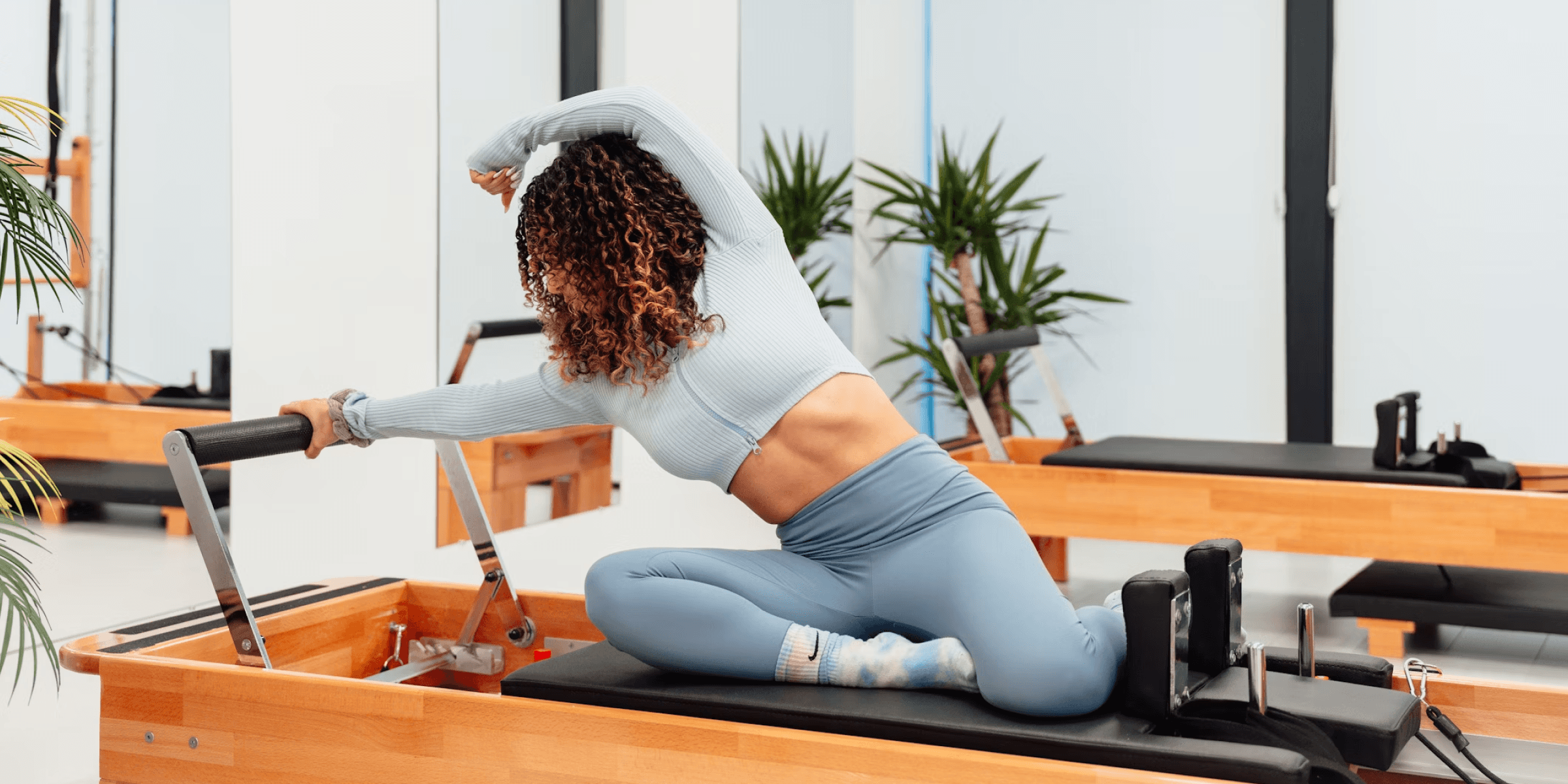 A woman doing pilates in a brightly lit studio.