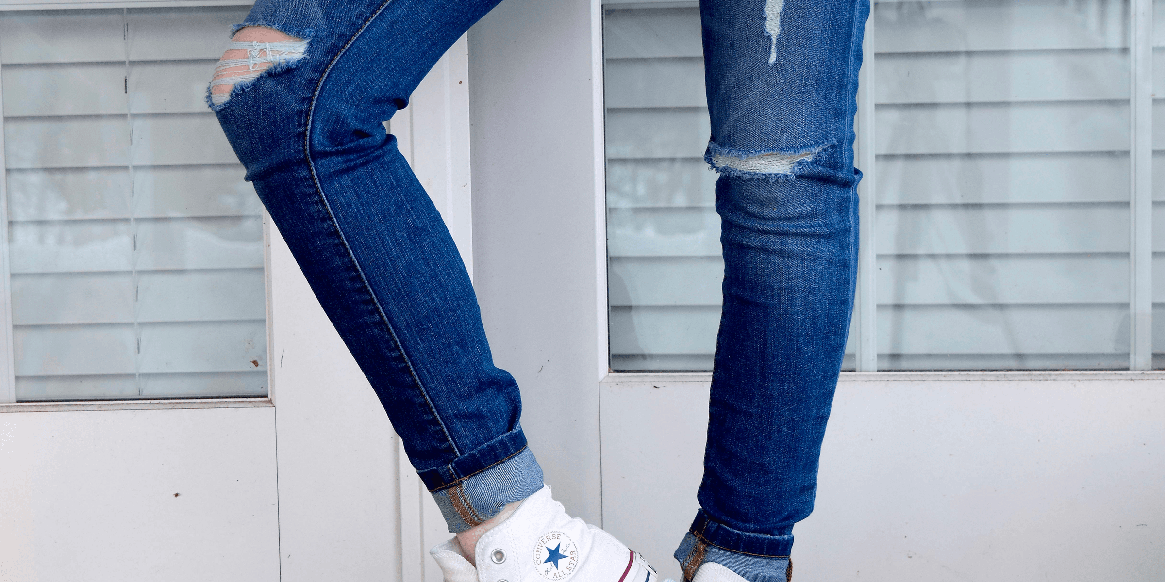 women's distressed blue denim jeans and pair of white Converse Allstar high-tops