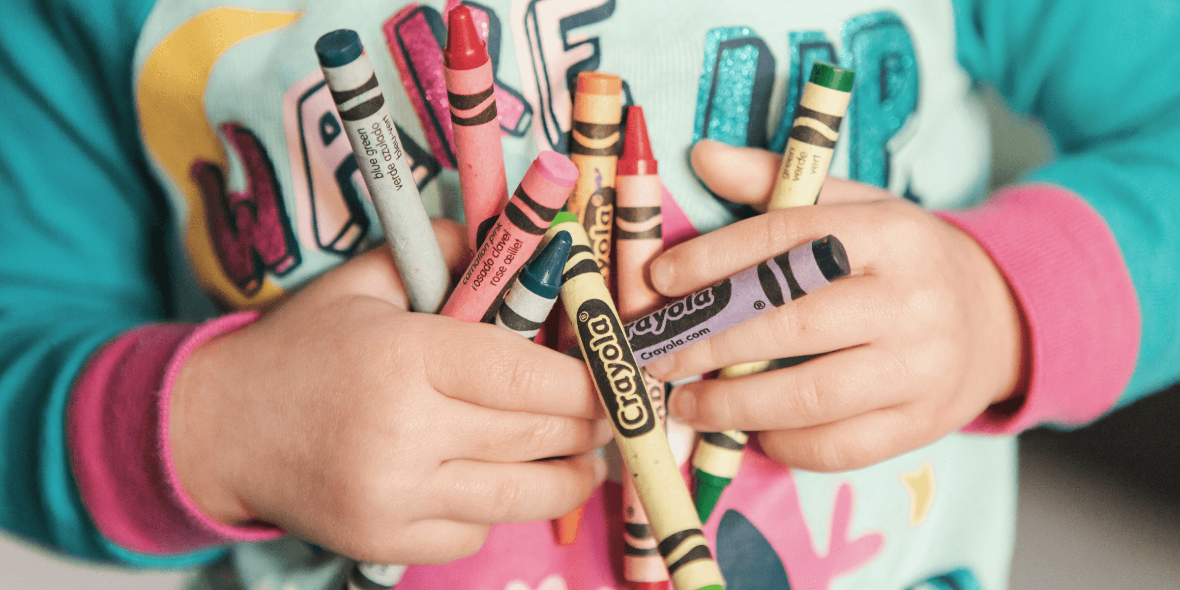 toddler holding assorted-color Crayola lot.