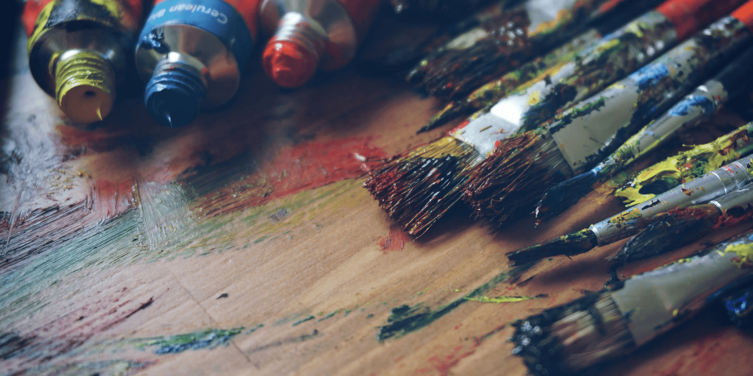 three paint tubes near paint brushes.