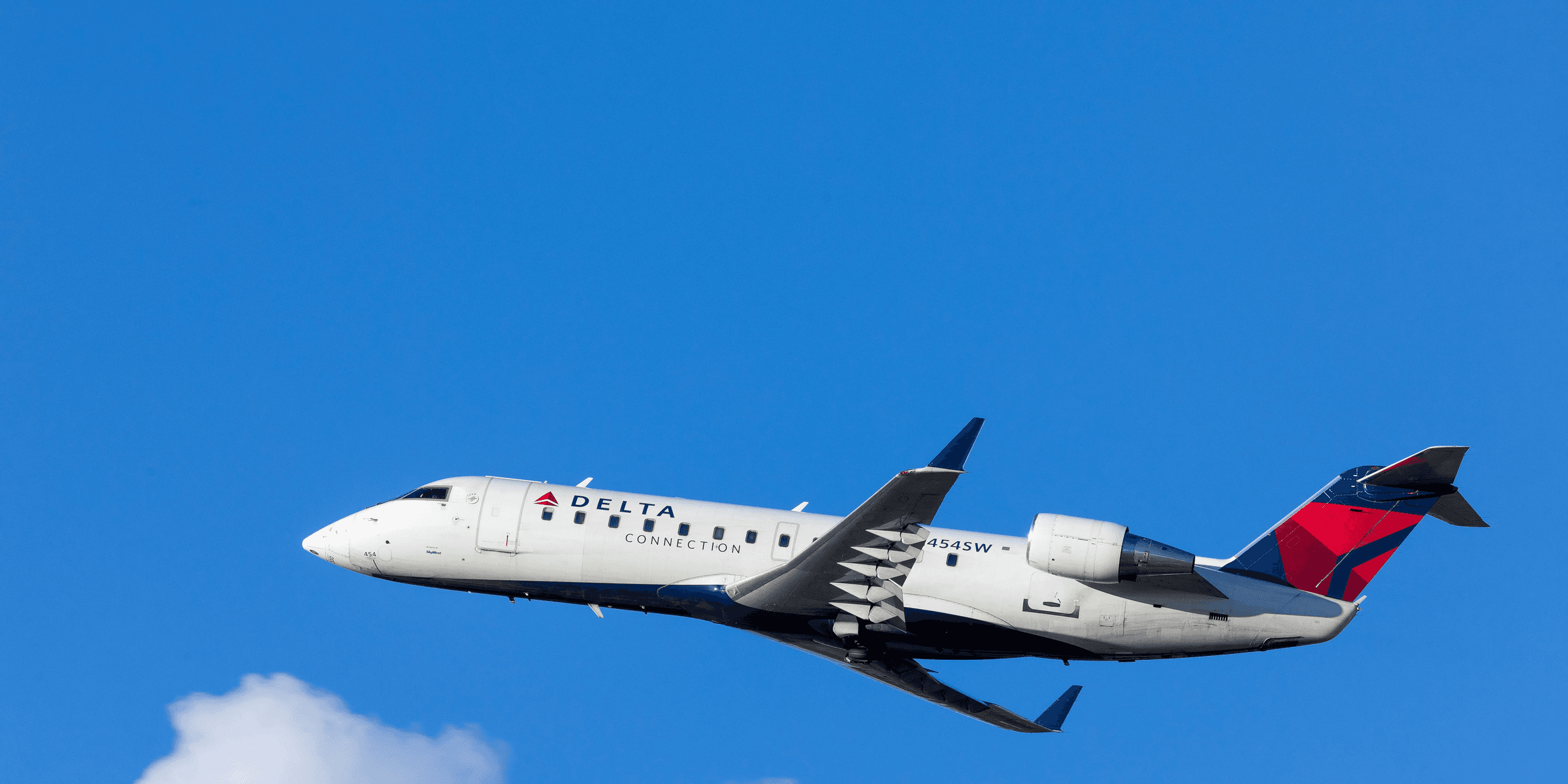 white, blue, and red Delta airways airliner on flight under white and blue cloudy sky.