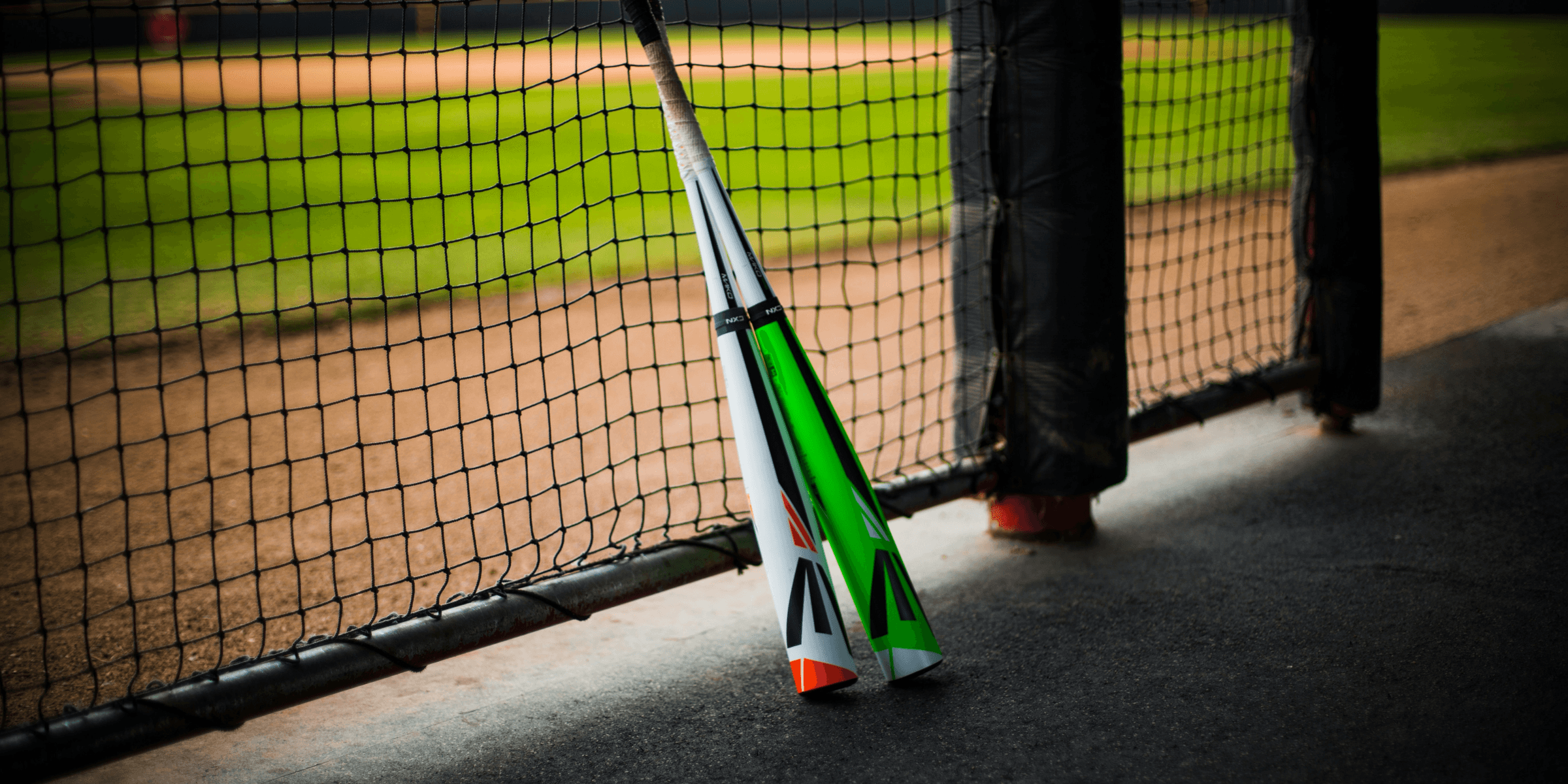 a baseball bat leaning against a fence on a baseball field