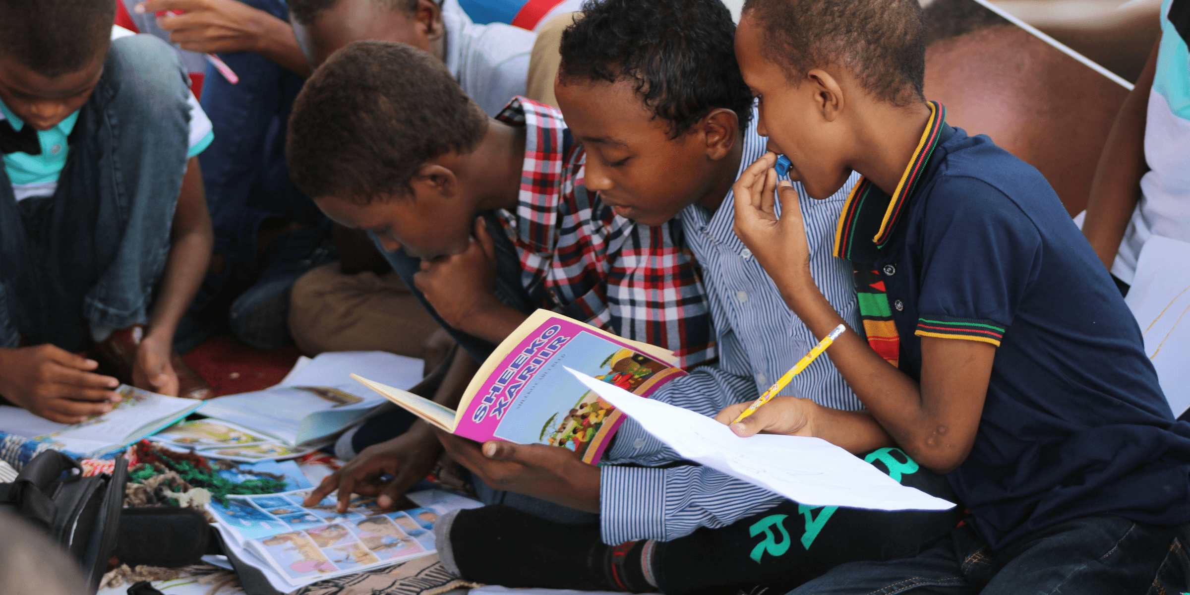 boy in blue and white plaid shirt reading book.
