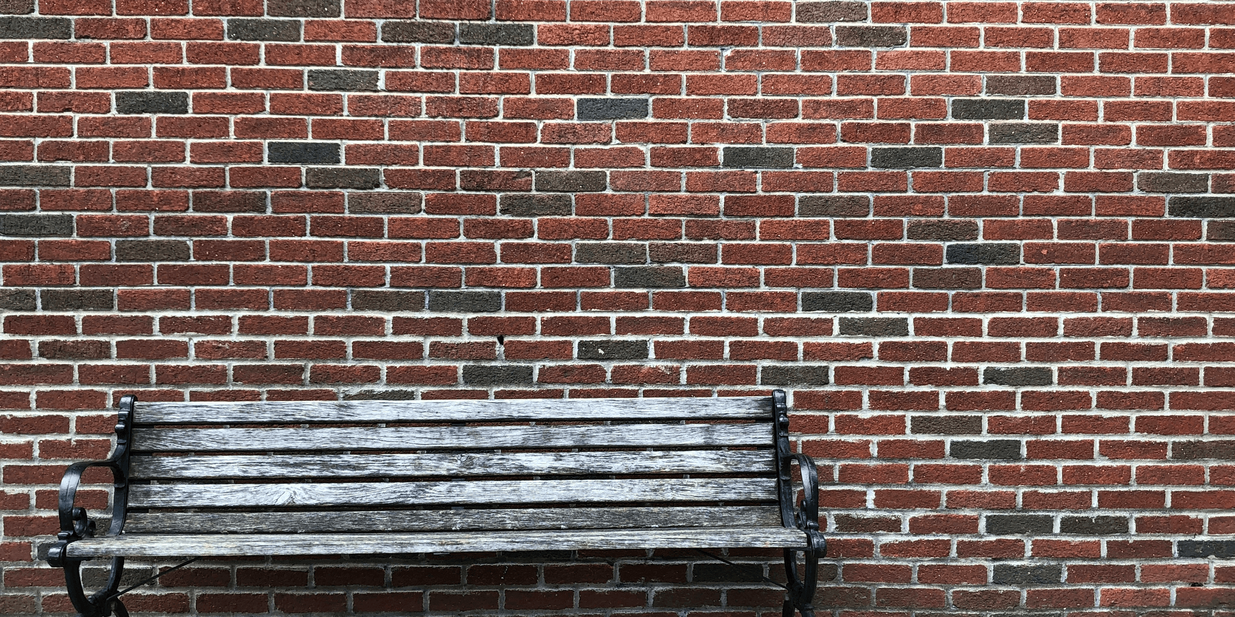 gray wooden bench beside brown wall.