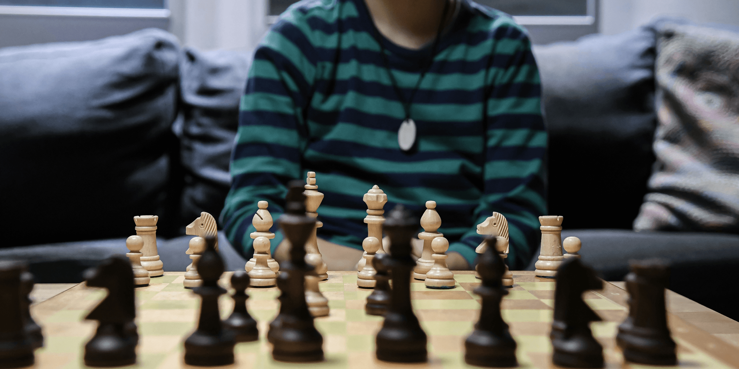 boy in green and black striped sweater playing chess.