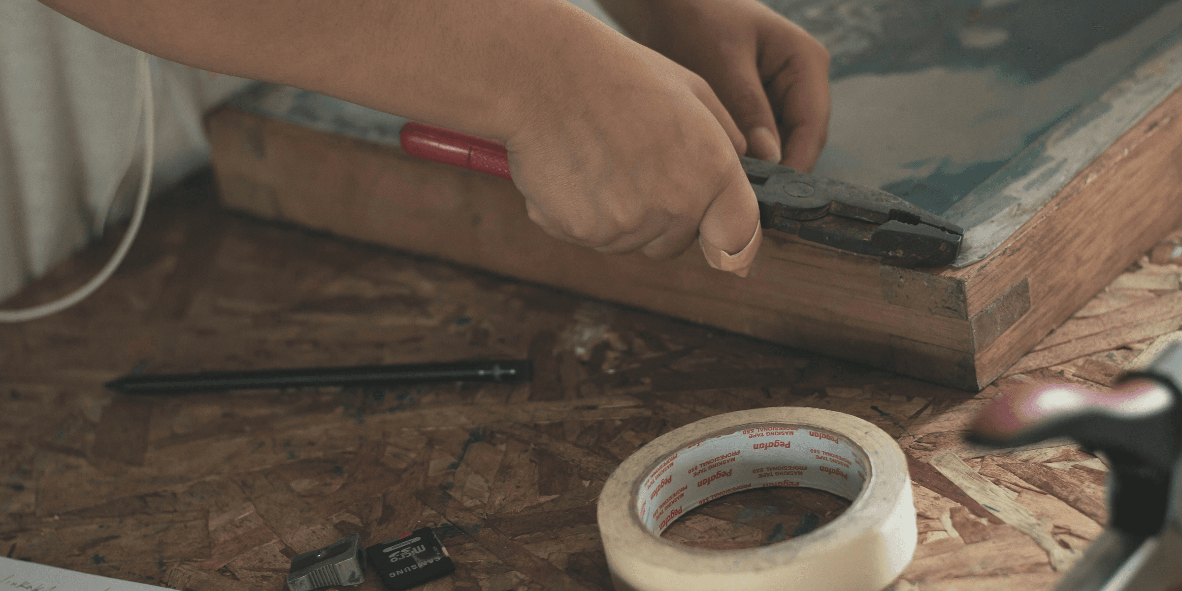 person holding pliers near adhesive tape