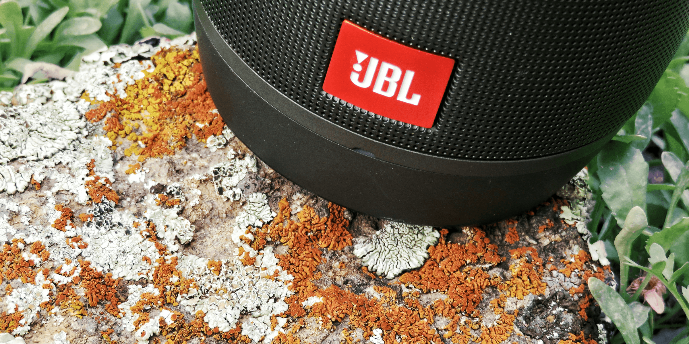 black jbl portable speaker on brown and white textile.