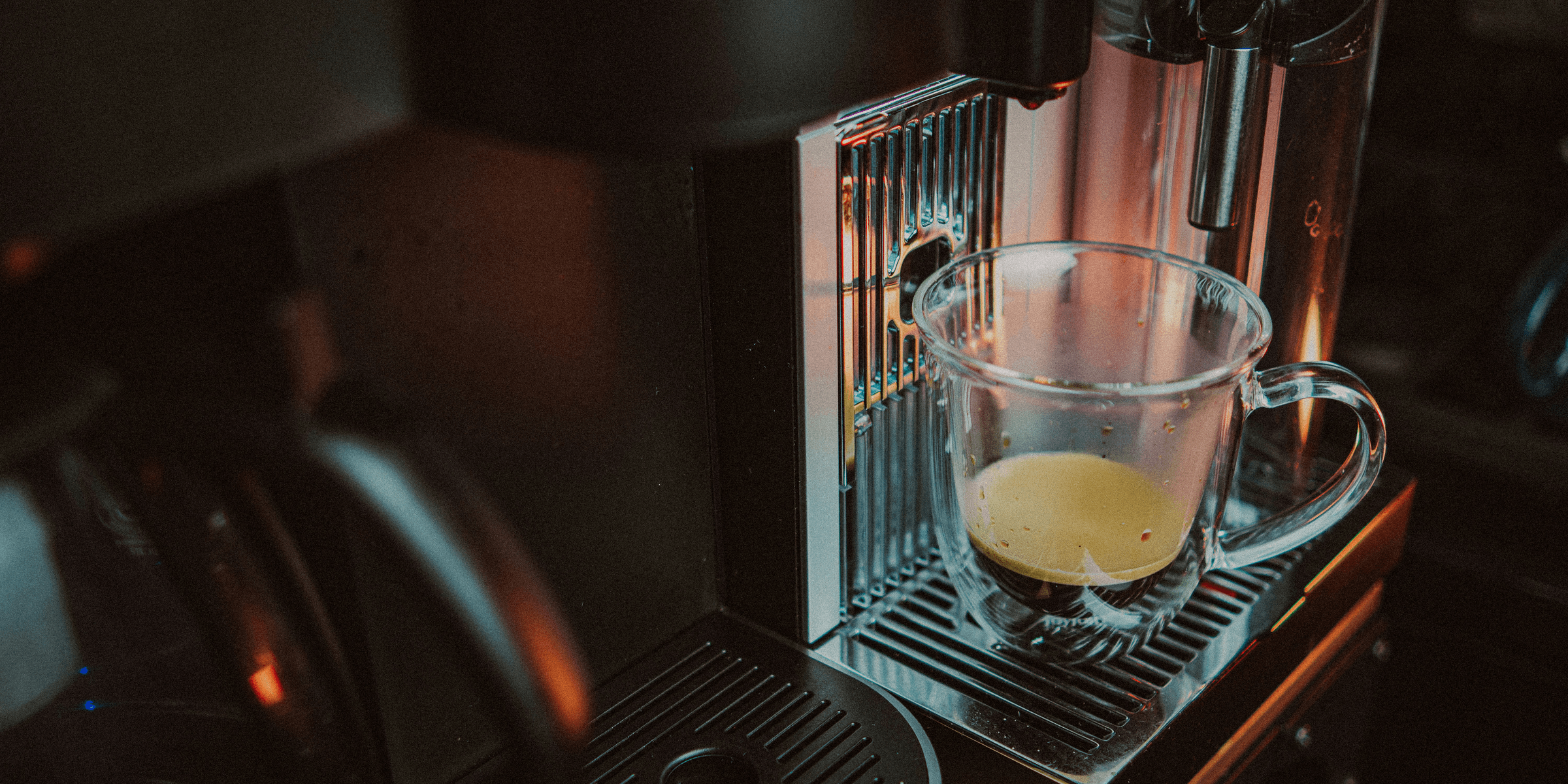 a glass of liquid on a coffee machine.
