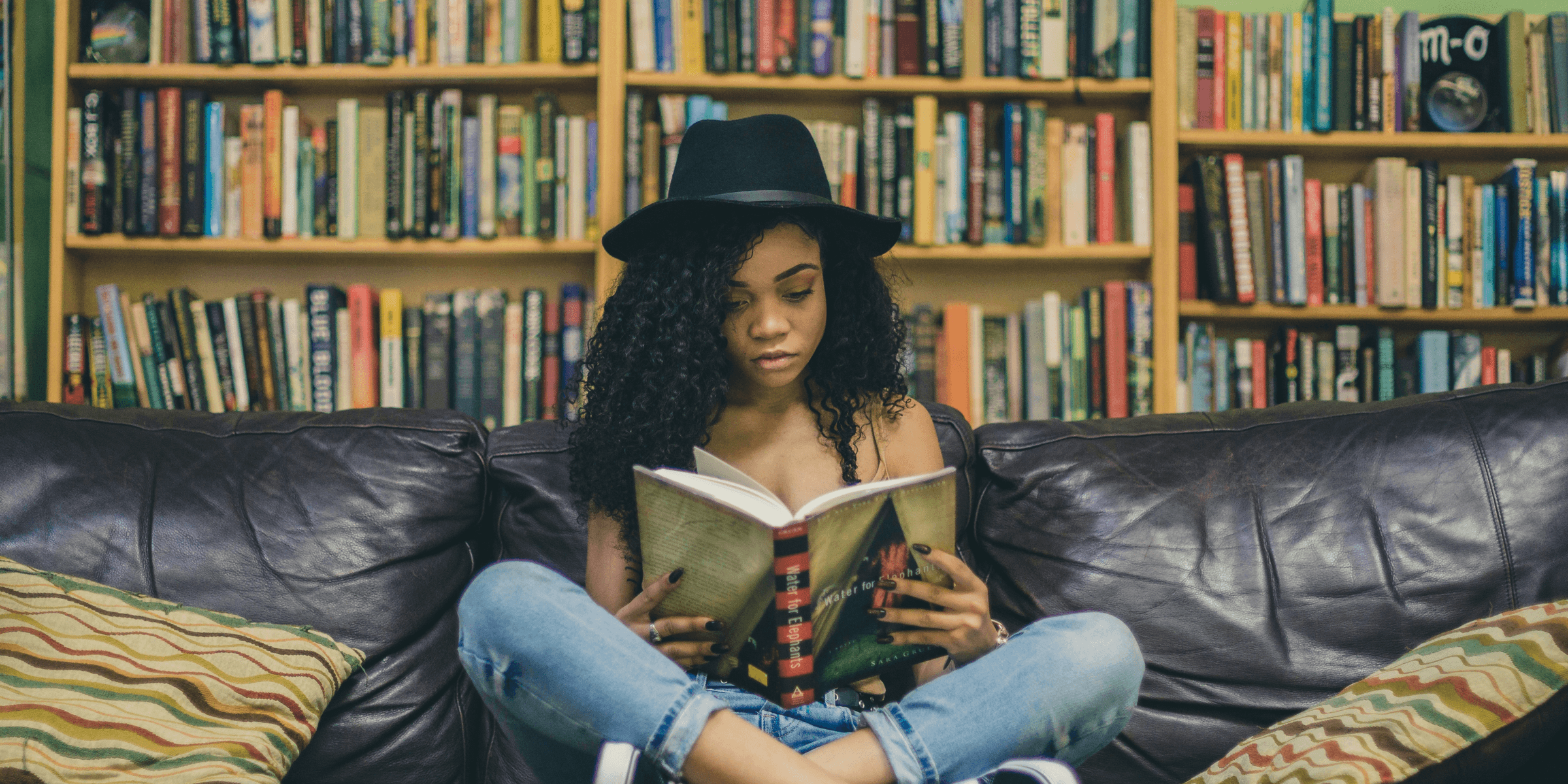 woman reading a book while sitting on black leather 3-seat couch.