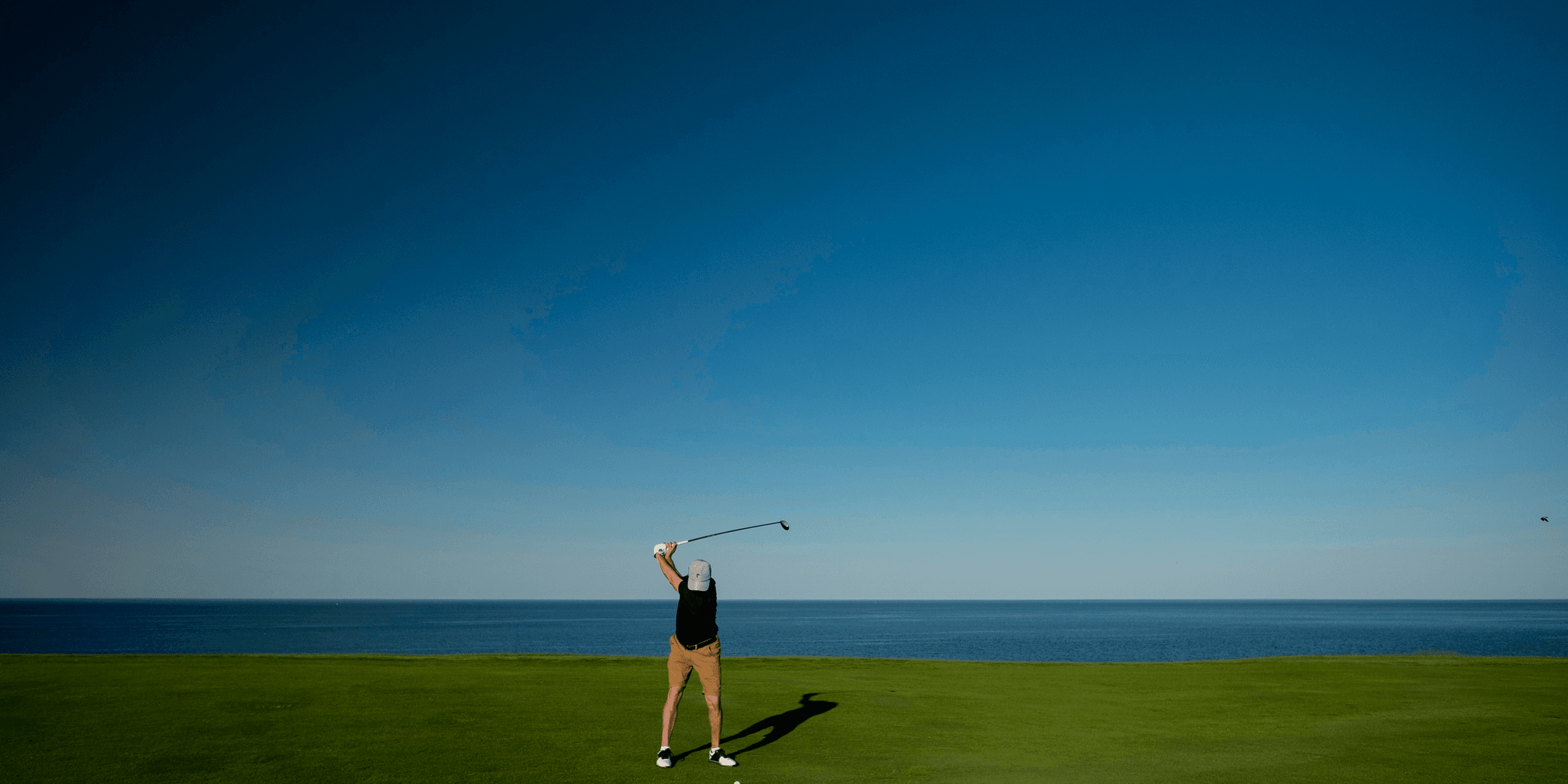 man standing on green grass field playing golf.