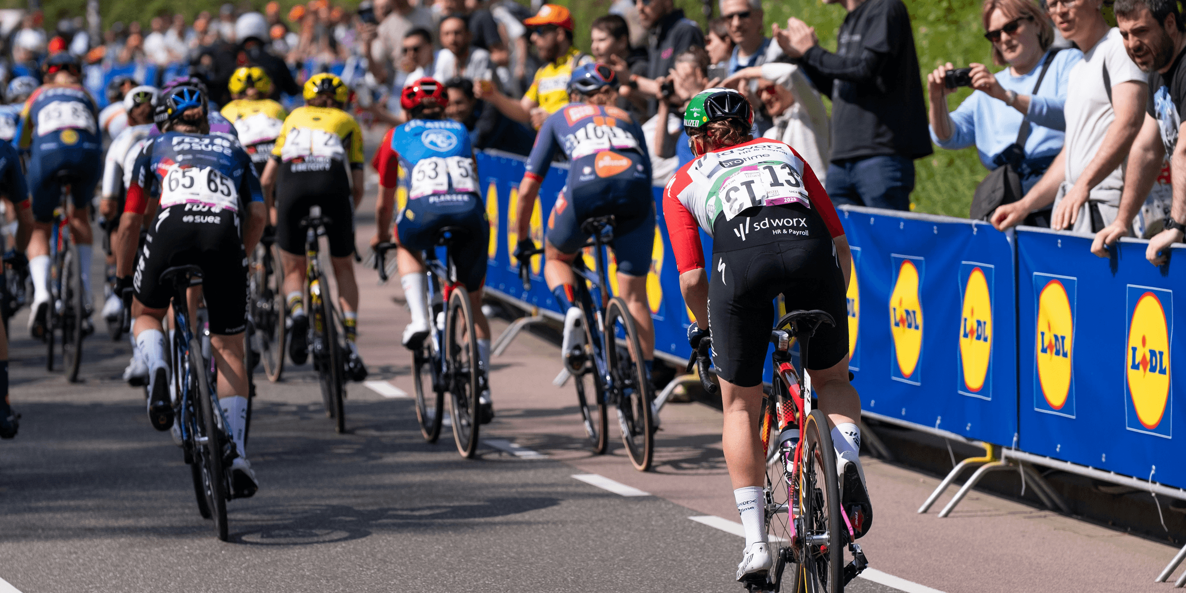 Cyclists race down a road with spectators watching..