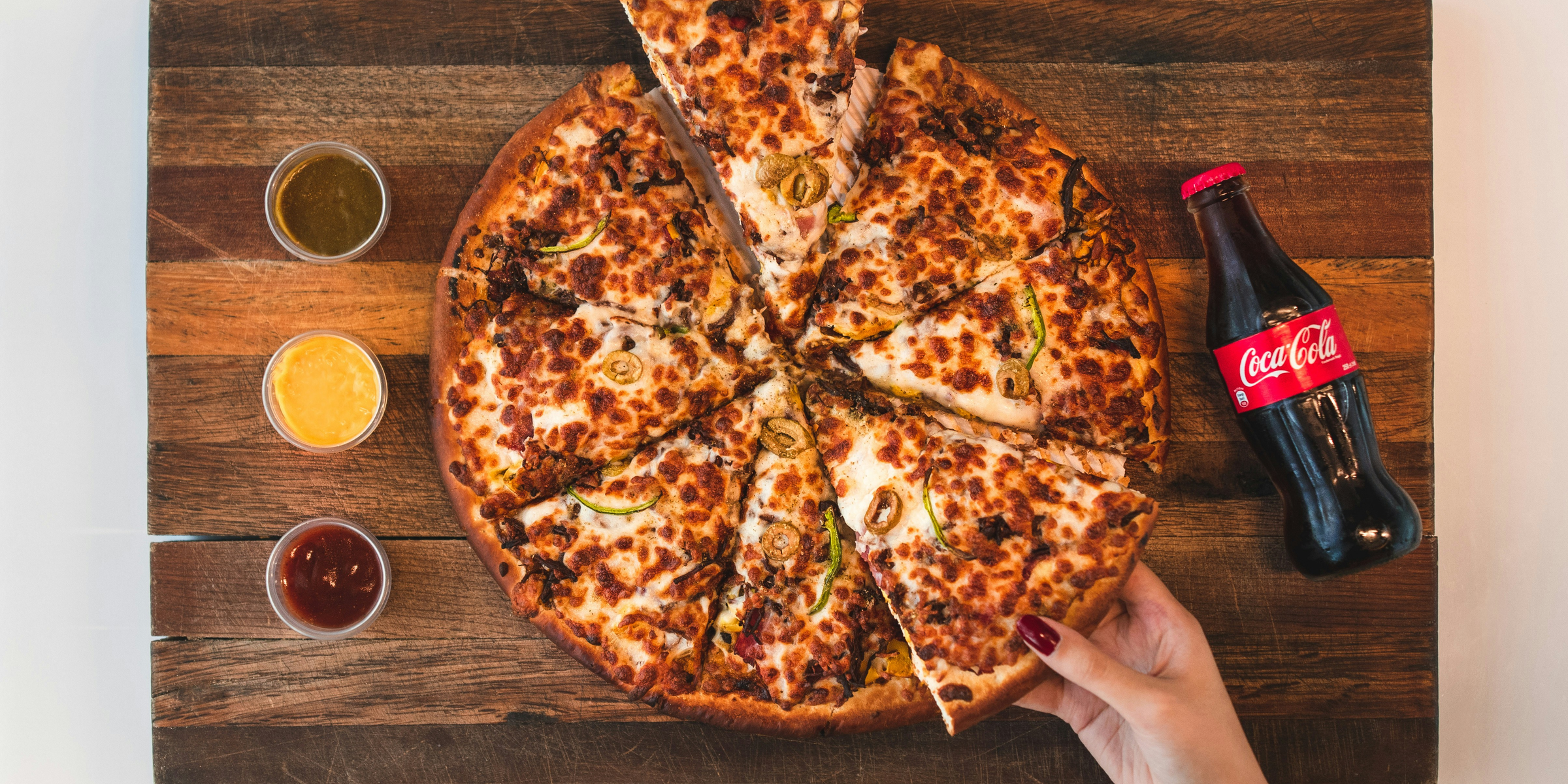 eight sliced pizza with Coca-Cola bottle beside.