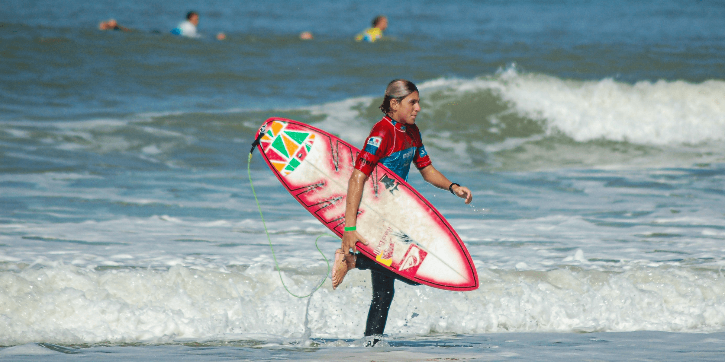 girl in red and black wet suit holding red and white surfboard on beach during daytime.