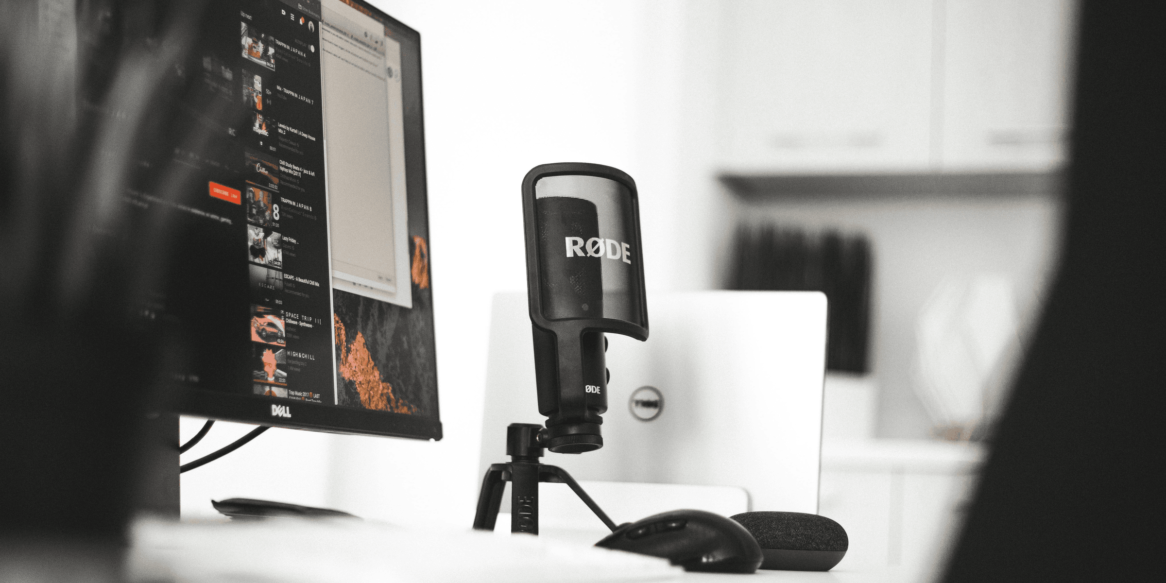 black Rode condenser microphone beside computer monitor.