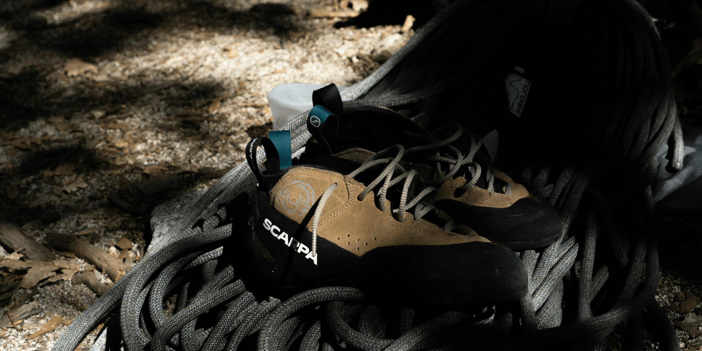 a pair of hiking shoes sitting on top of a pile of rope