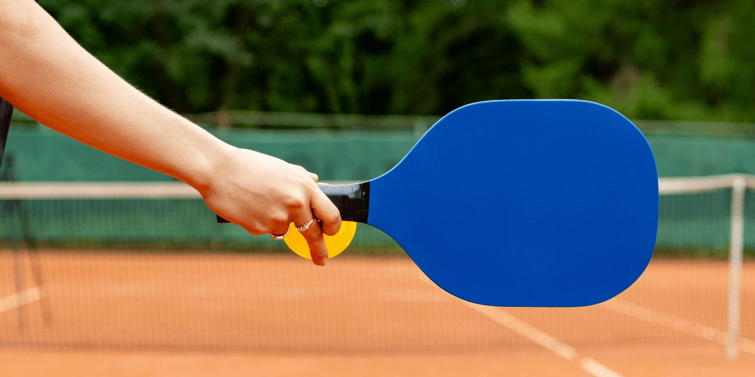 a person holding a ping pong paddle on a tennis court.