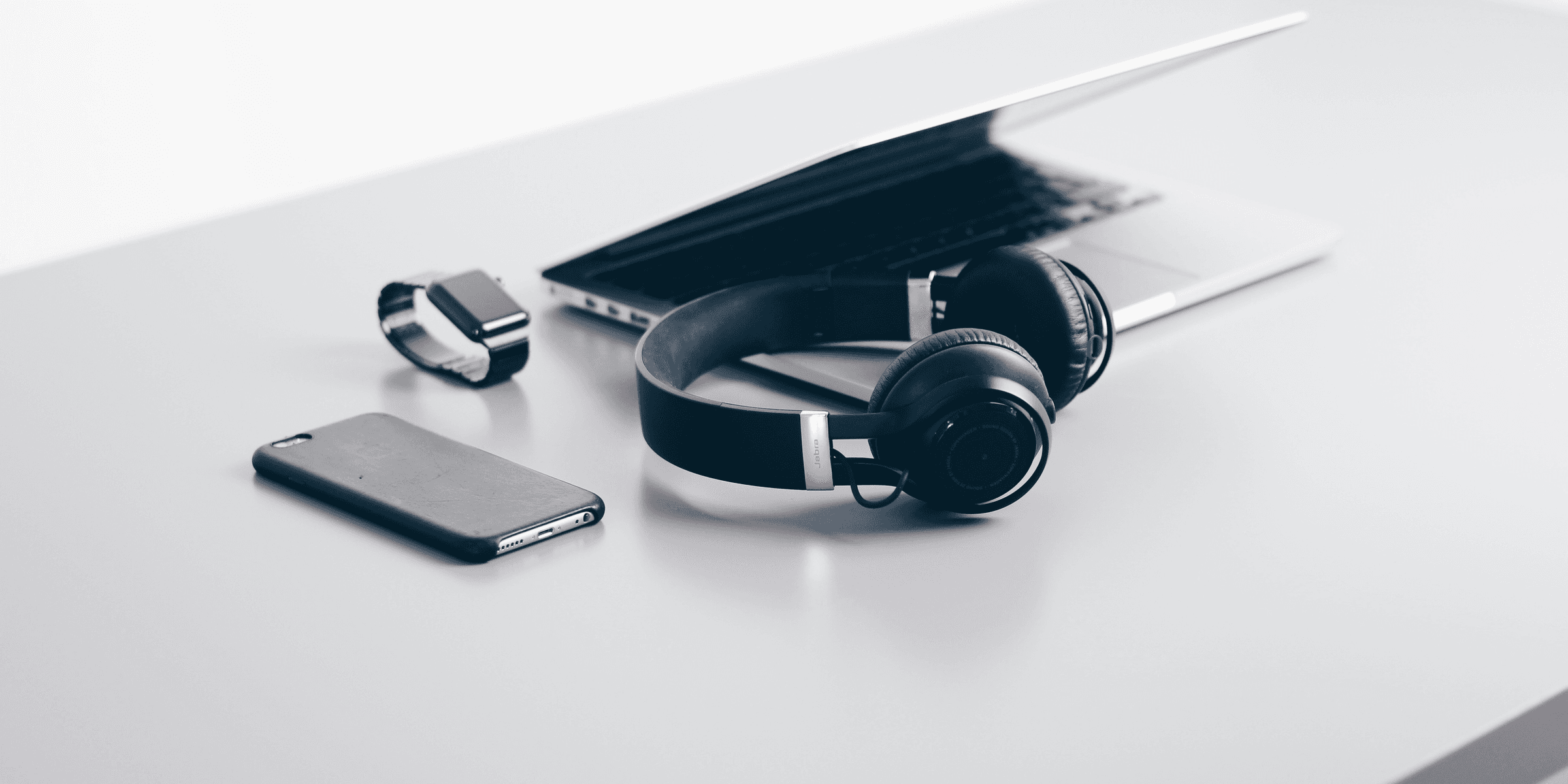 black cordless headphones beside closed black laptop computer and smartphone