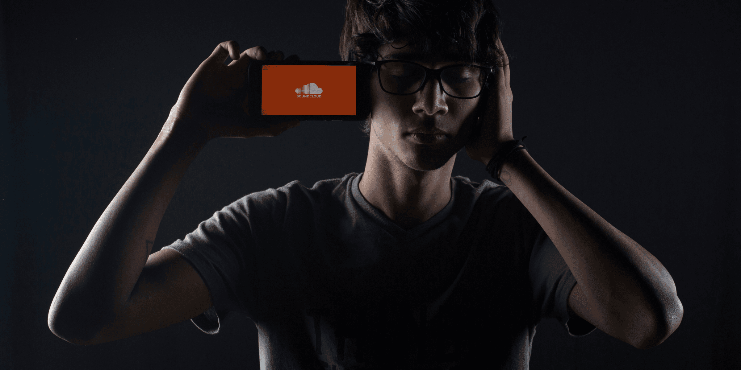 man listening to Soundcloud music on smartphone.