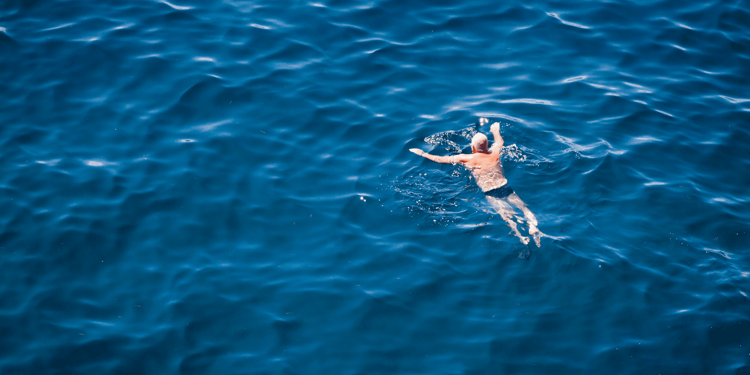 man swimming on body of water.