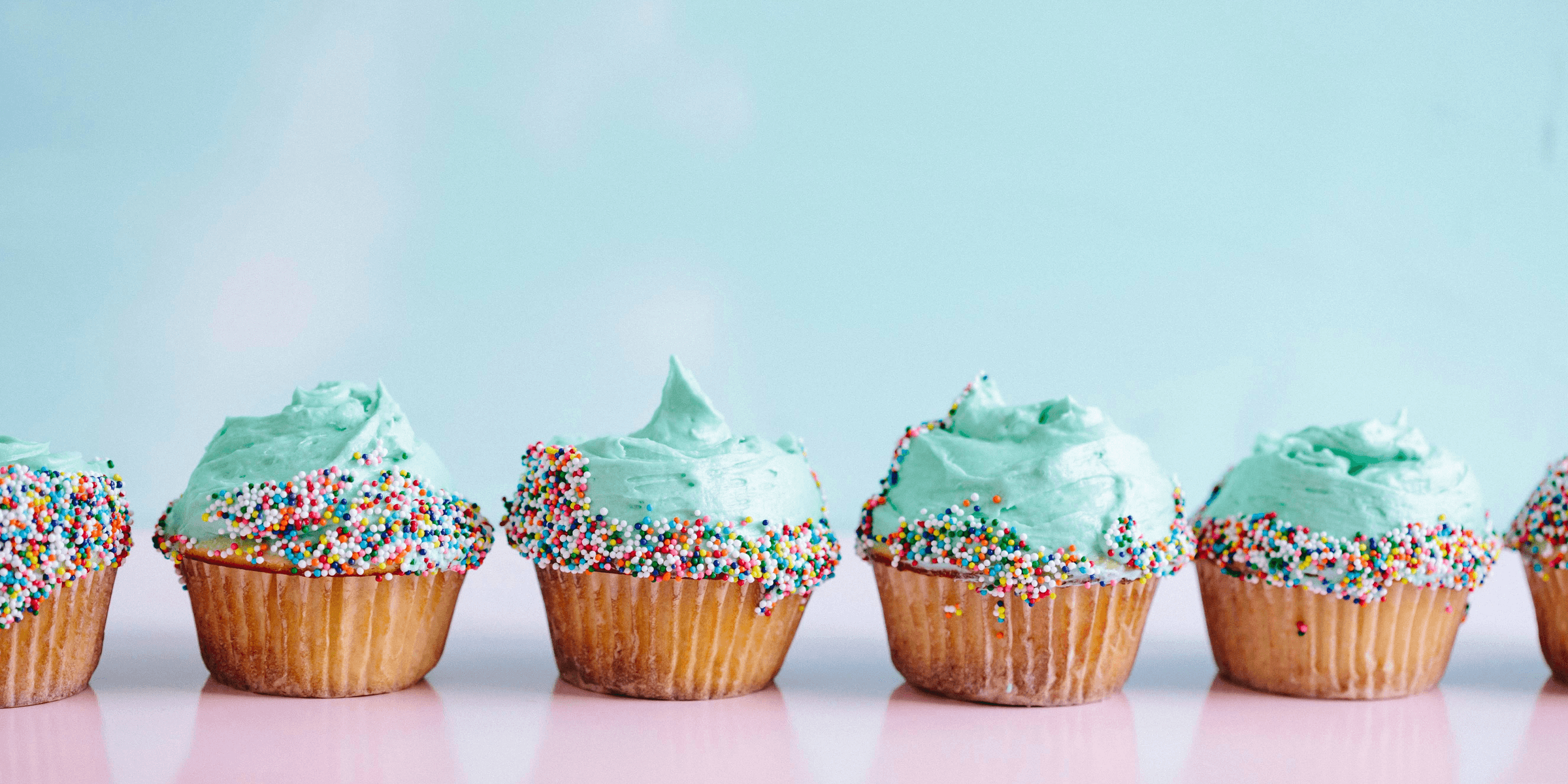 six teal icing cupcakes with sprinkles.