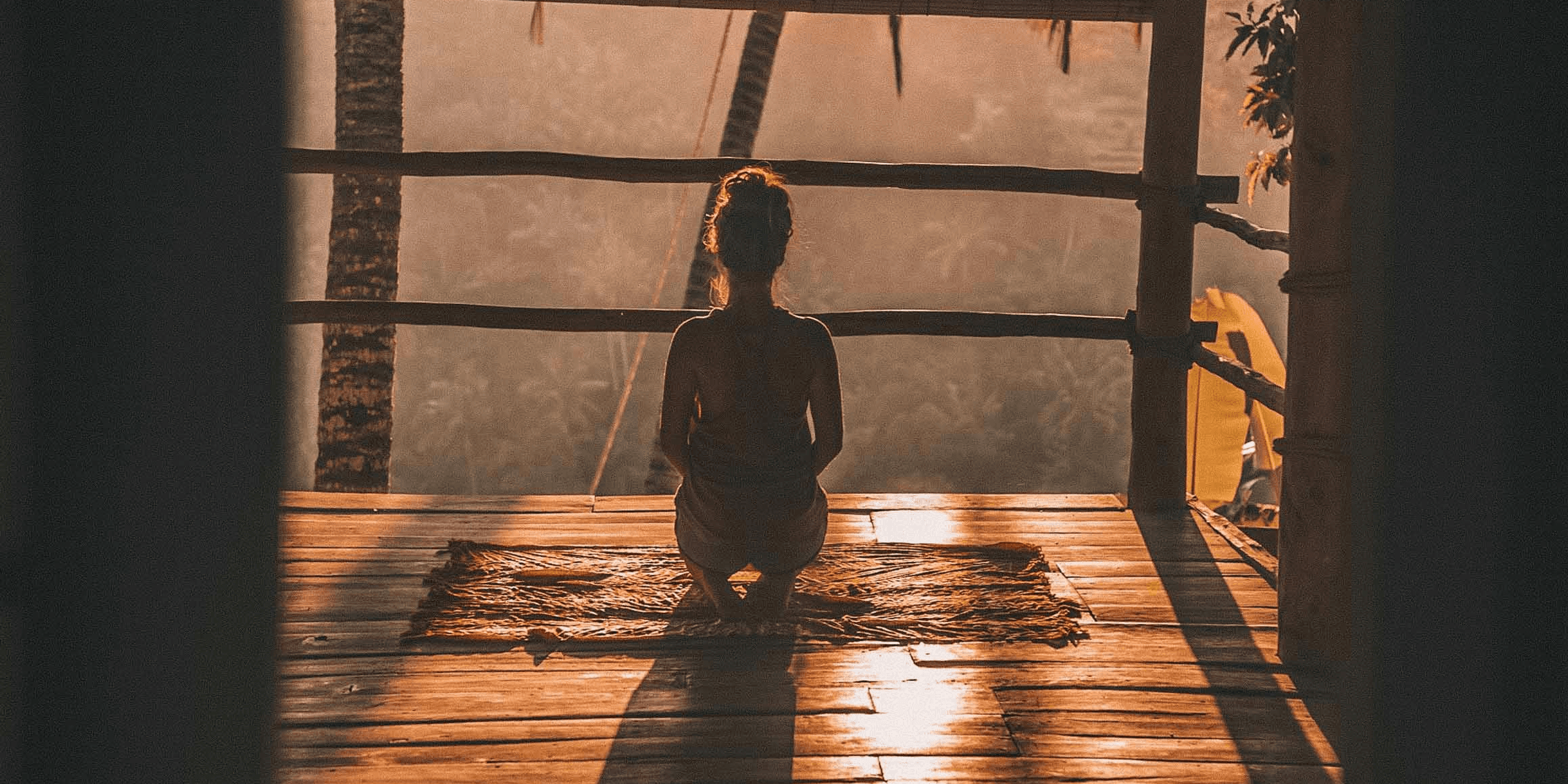 woman meditating on floor with overlooking view of trees