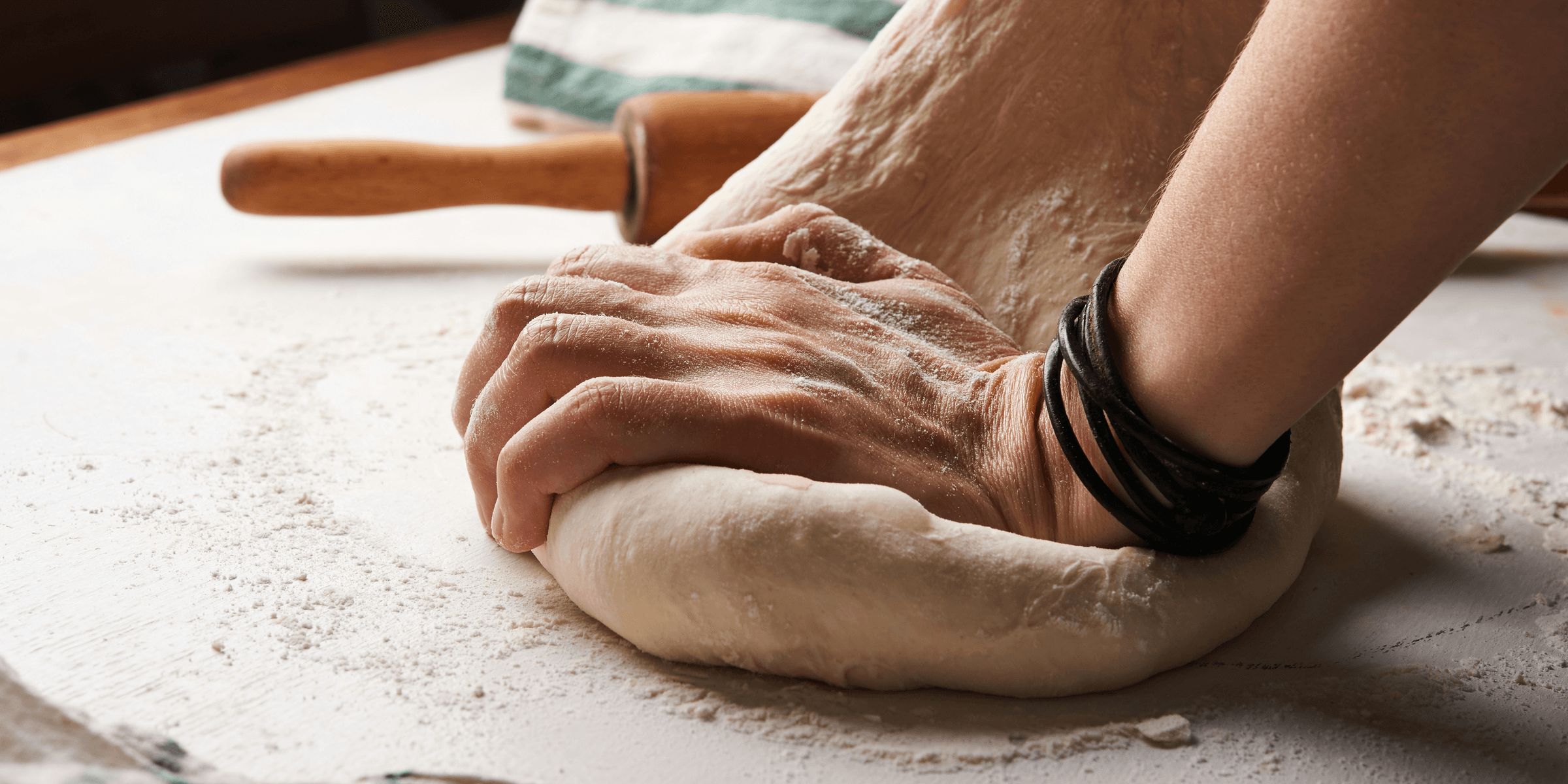 person making dough beside brown wooden rolling pin.