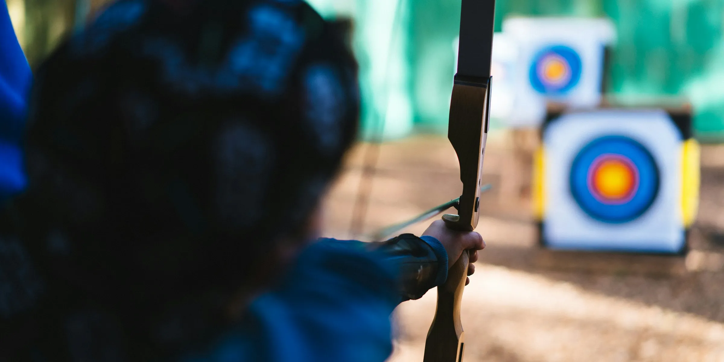 a woman is aiming a bow at a target