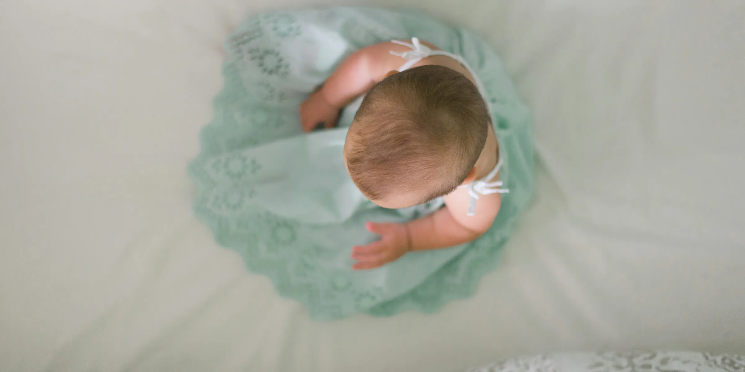 baby sitting on white textile