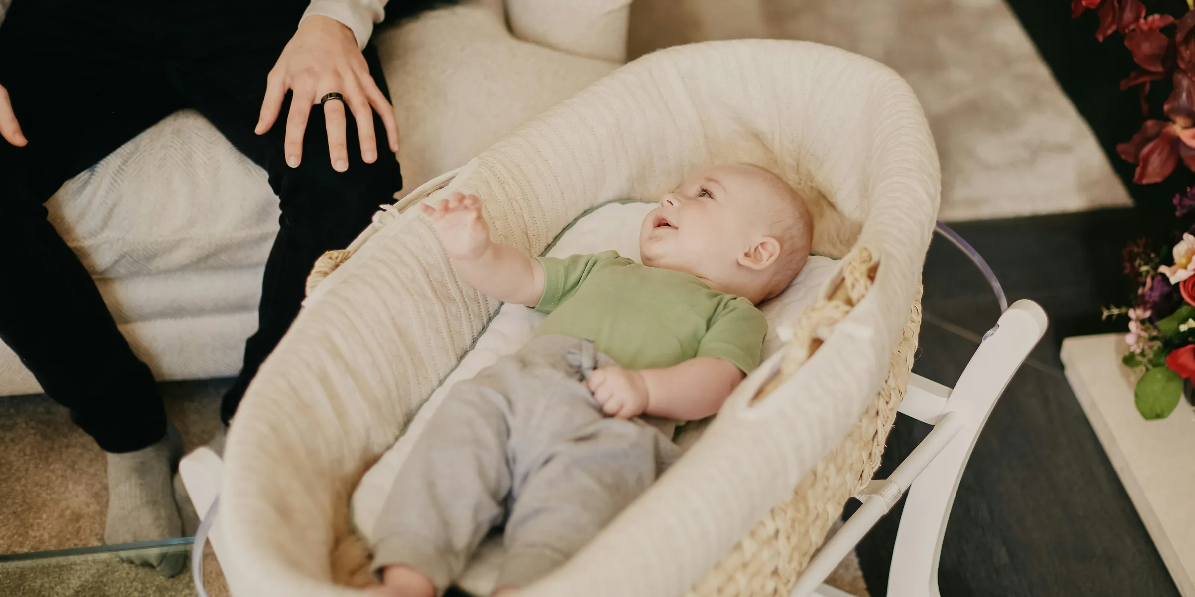 baby in green onesie lying on white and brown crib