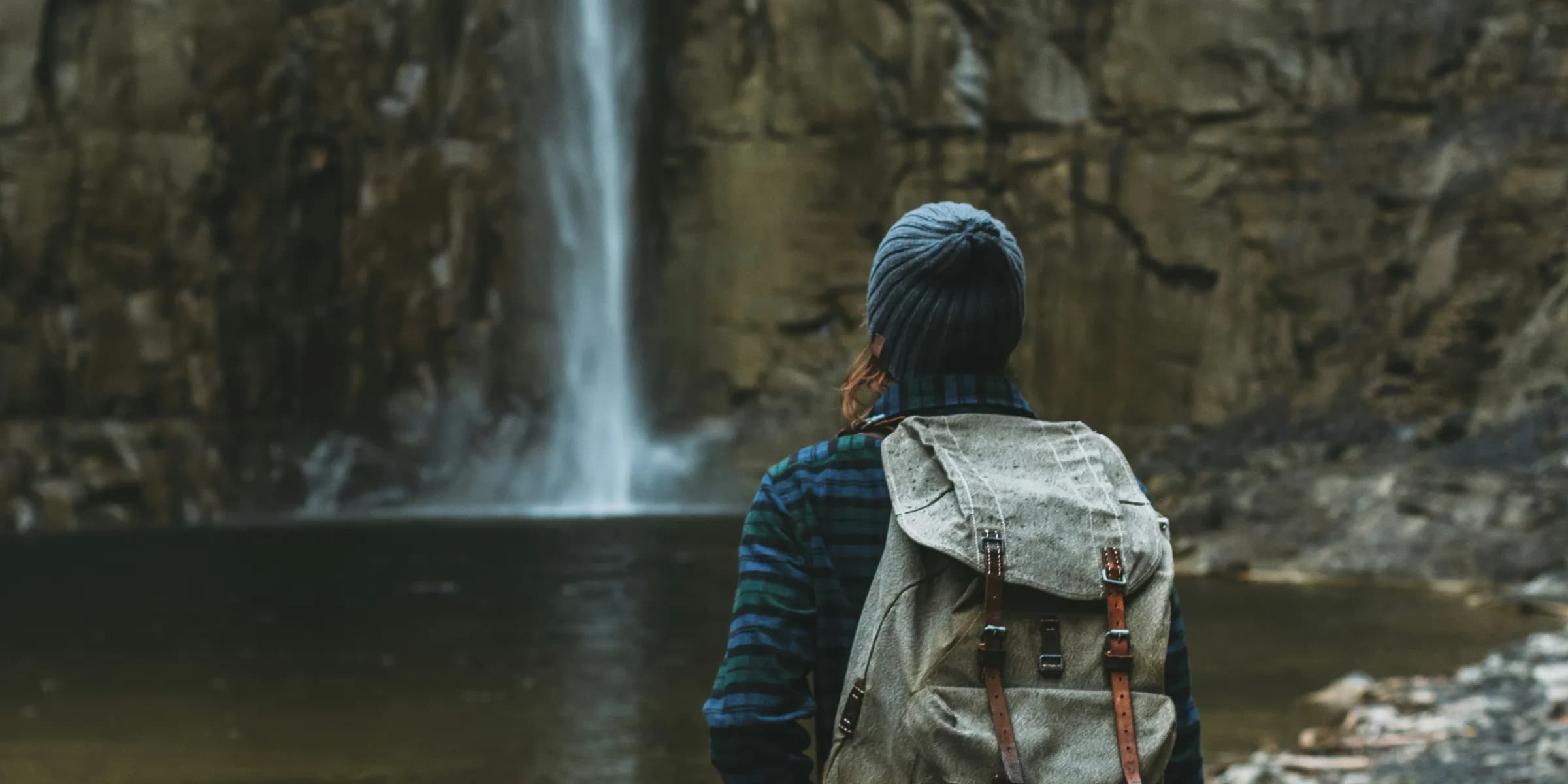 woman with backpack facing waterfalls