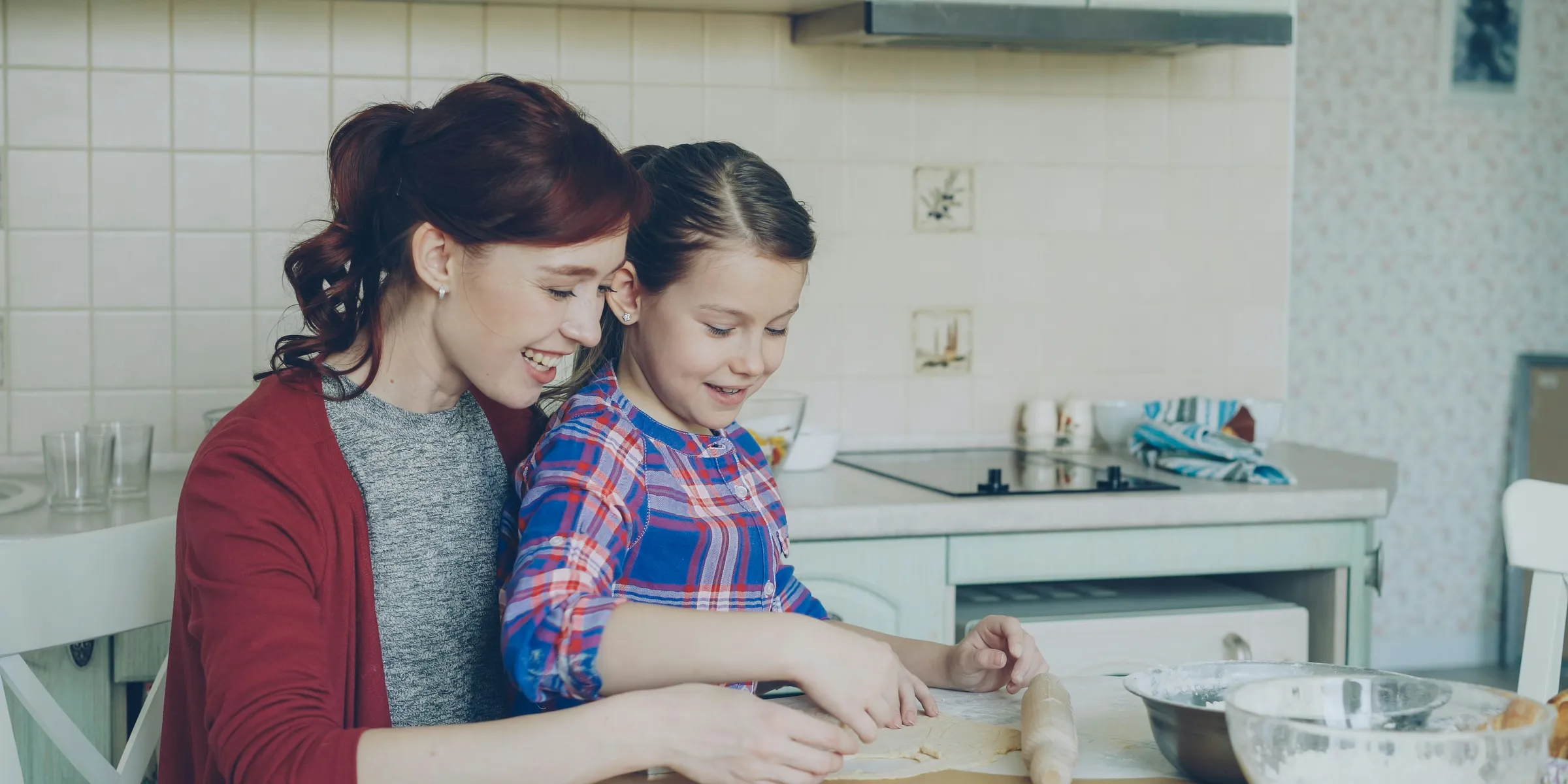 Mother and daughter happily bake together in the kitchen.