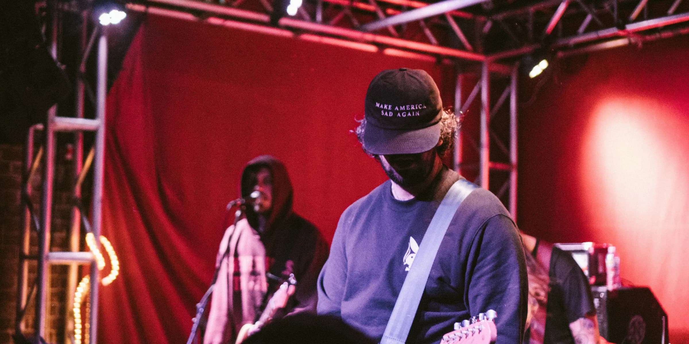 man playing guitar near man singing at stage