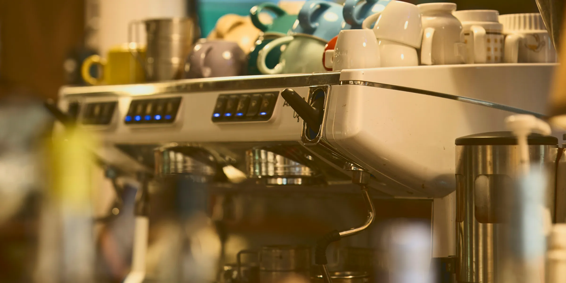 Espresso machine with stacked cups at a coffee shop.