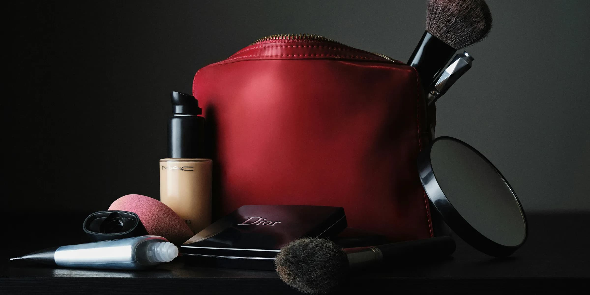 red leather bag beside black makeup brush