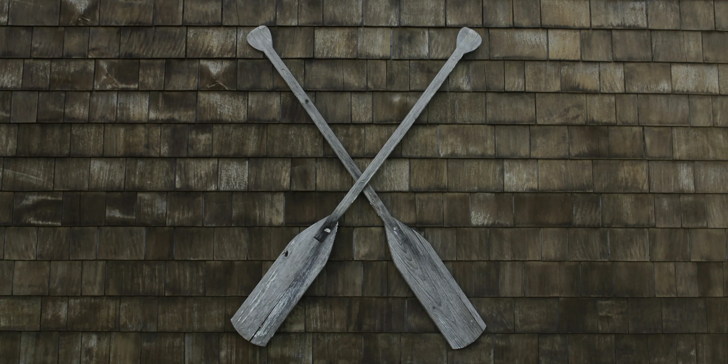 two gray wooden boat paddles hanged on wall