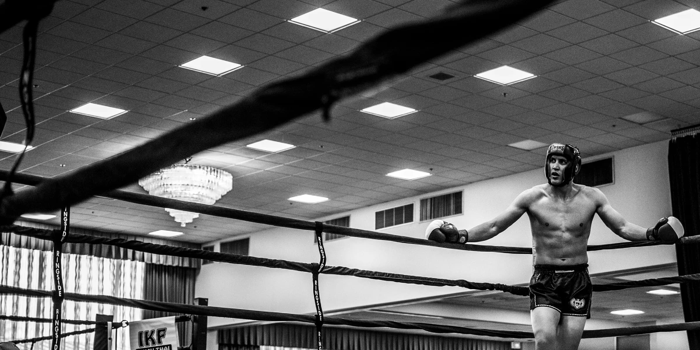 man leaning on boxing ring's pole