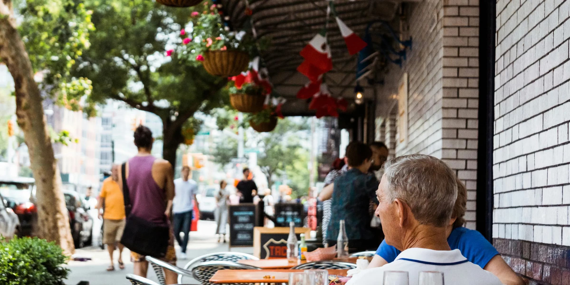 people dining outside restaurant near car parks under trees