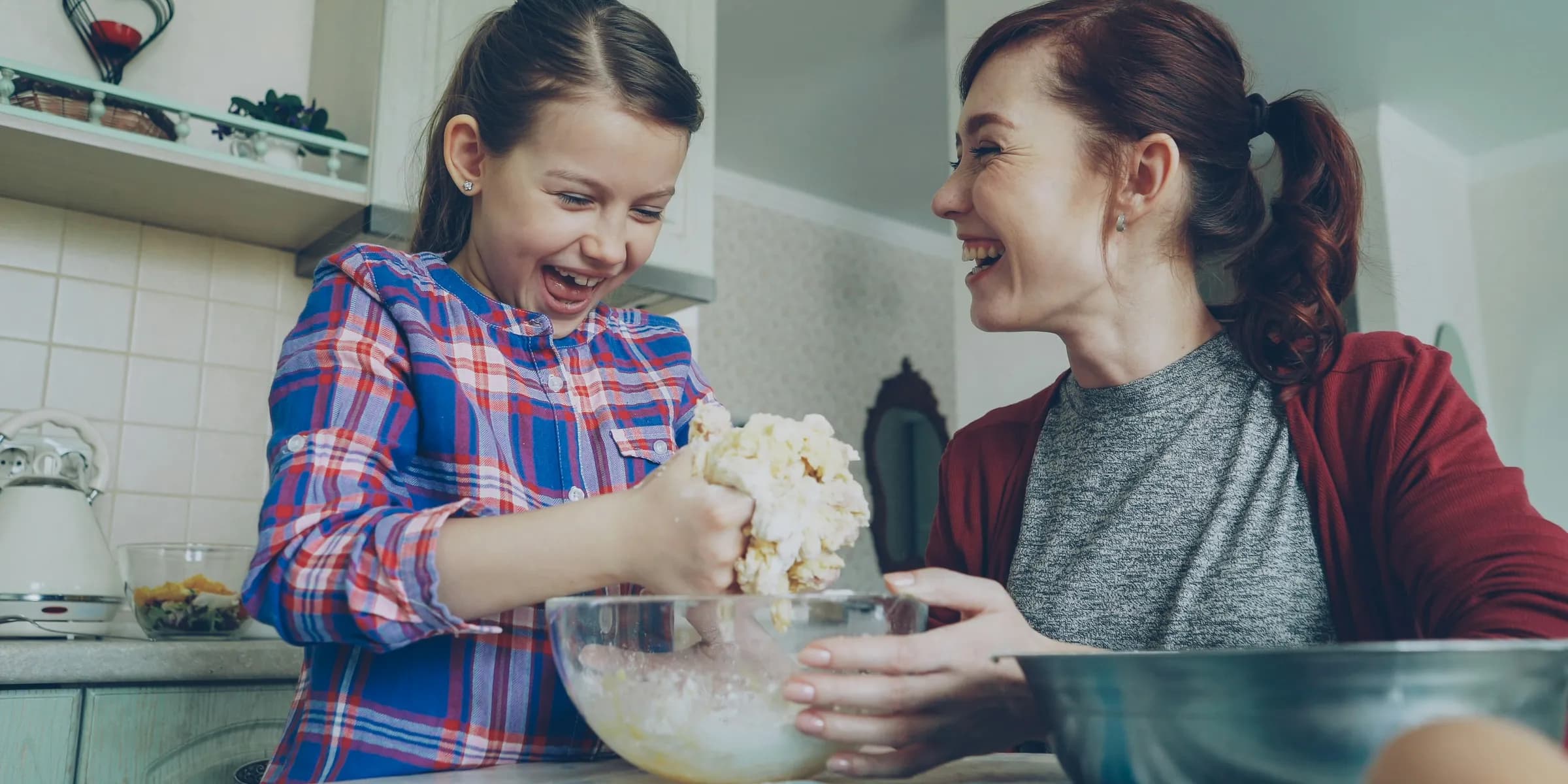 Mother and daughter bake together, laughing.