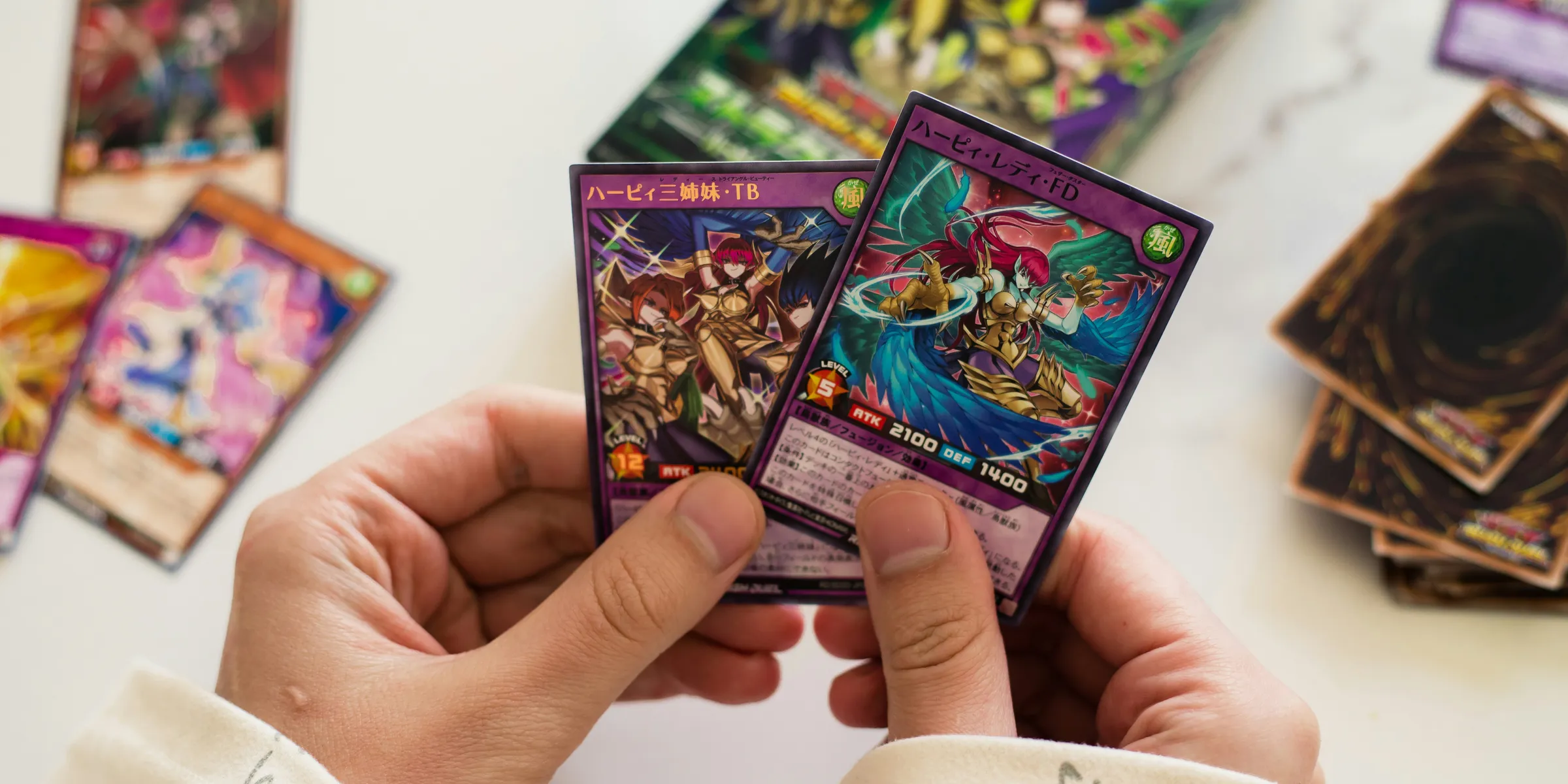 Hands are holding up two yu-gi-oh! cards.