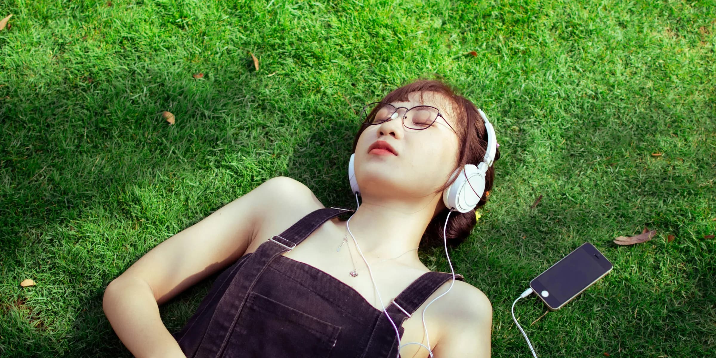 a woman laying on the grass listening to music