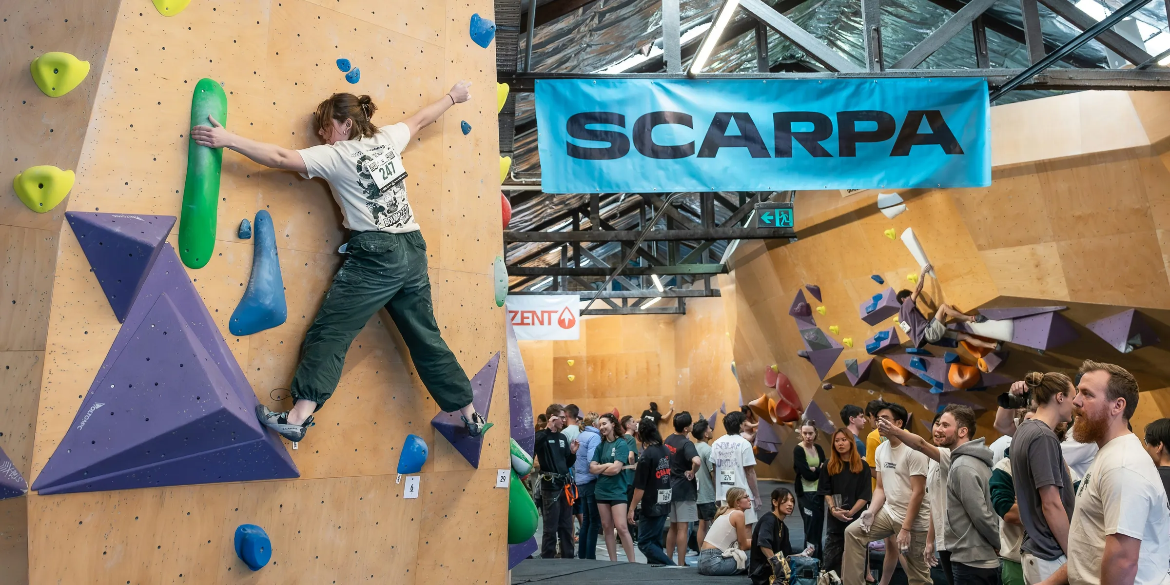 A group of people standing around a climbing wall
