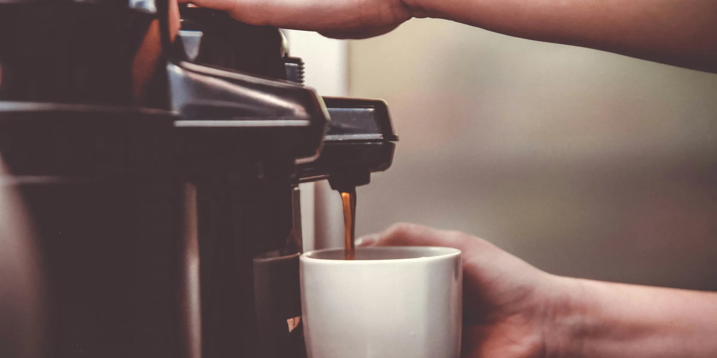 person using coffeemaker with white ceramic mug