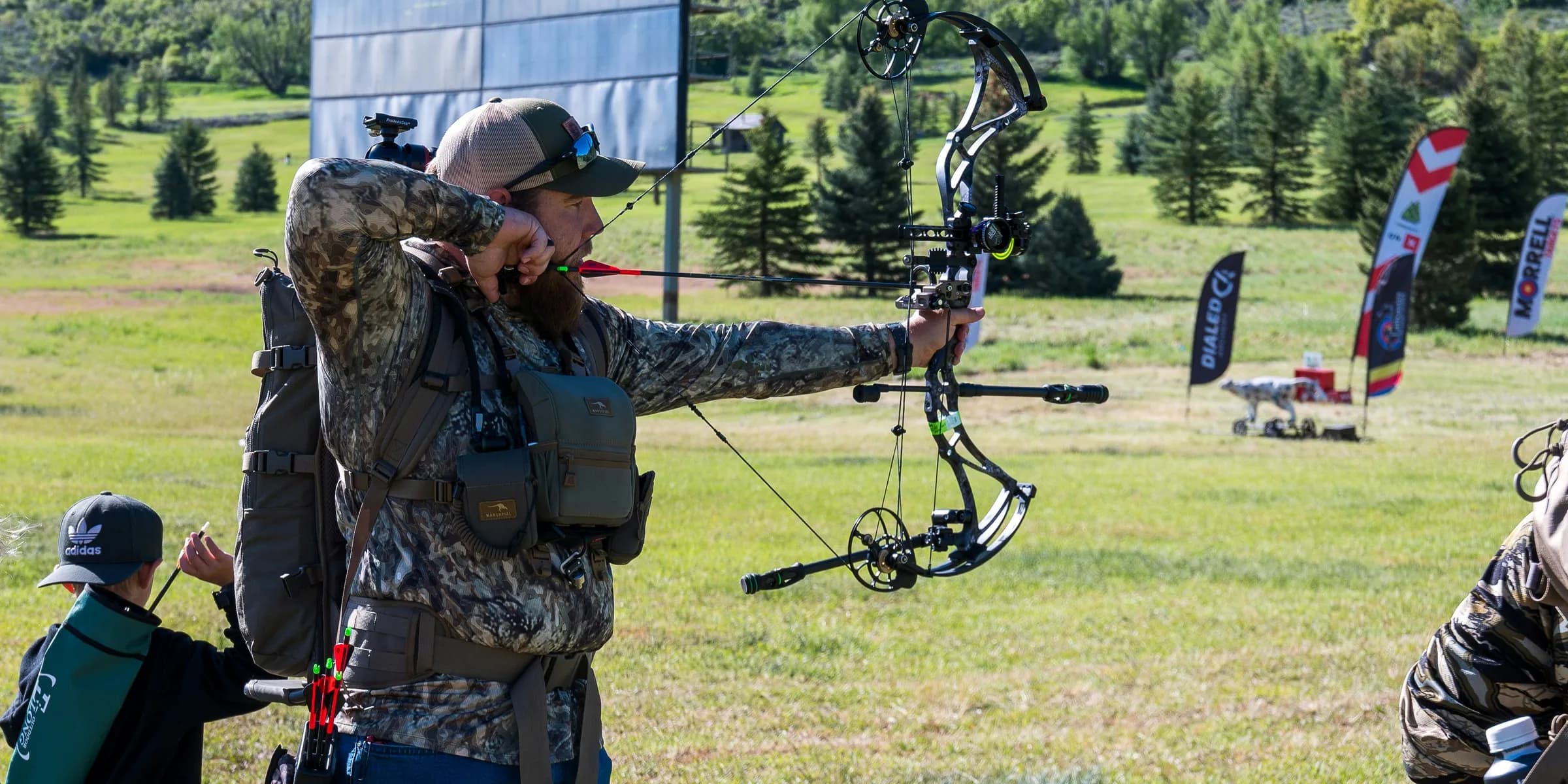 A man holding a bow while standing in a field