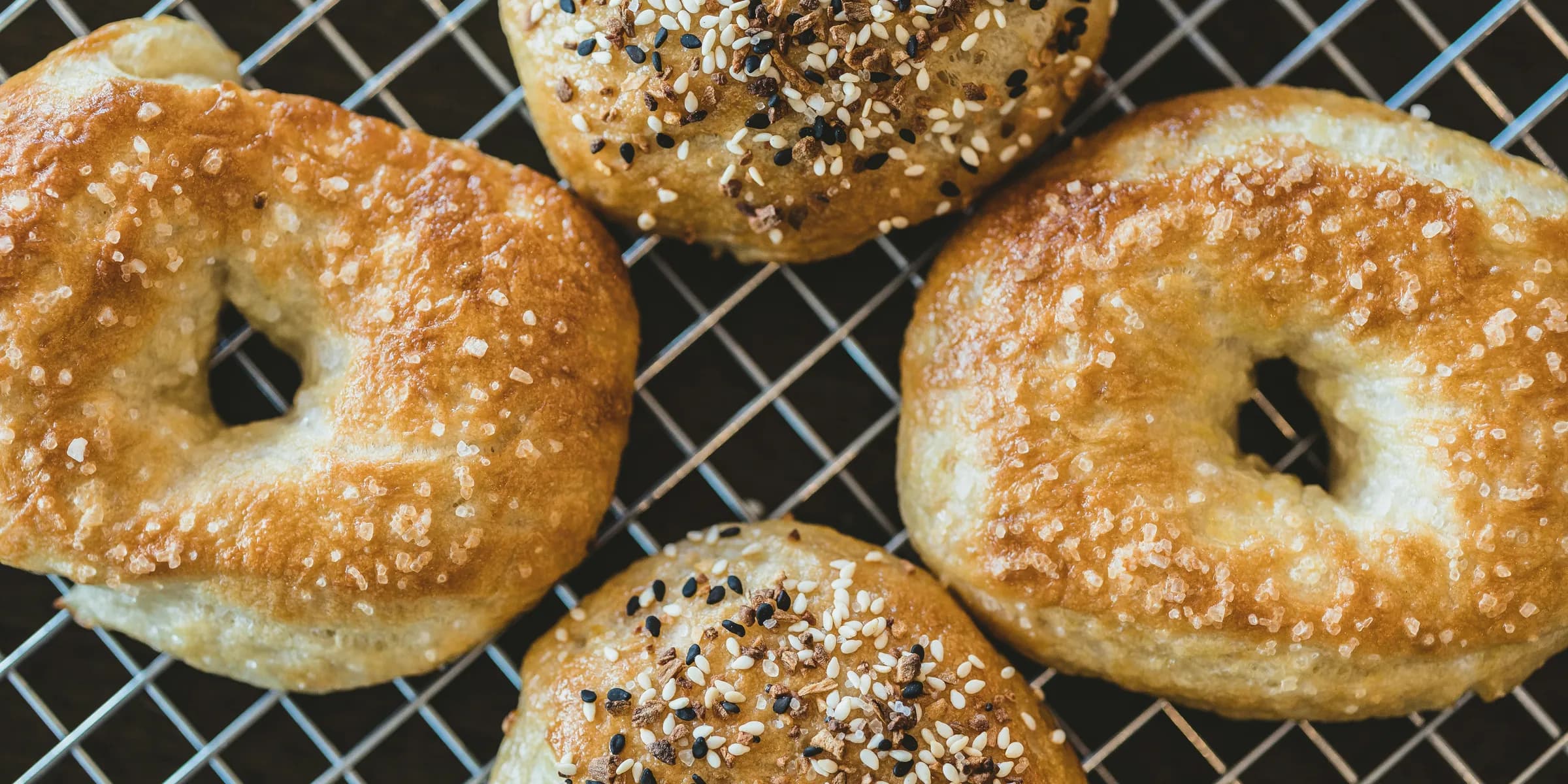 four bagels with sesame seeds on a cooling rack